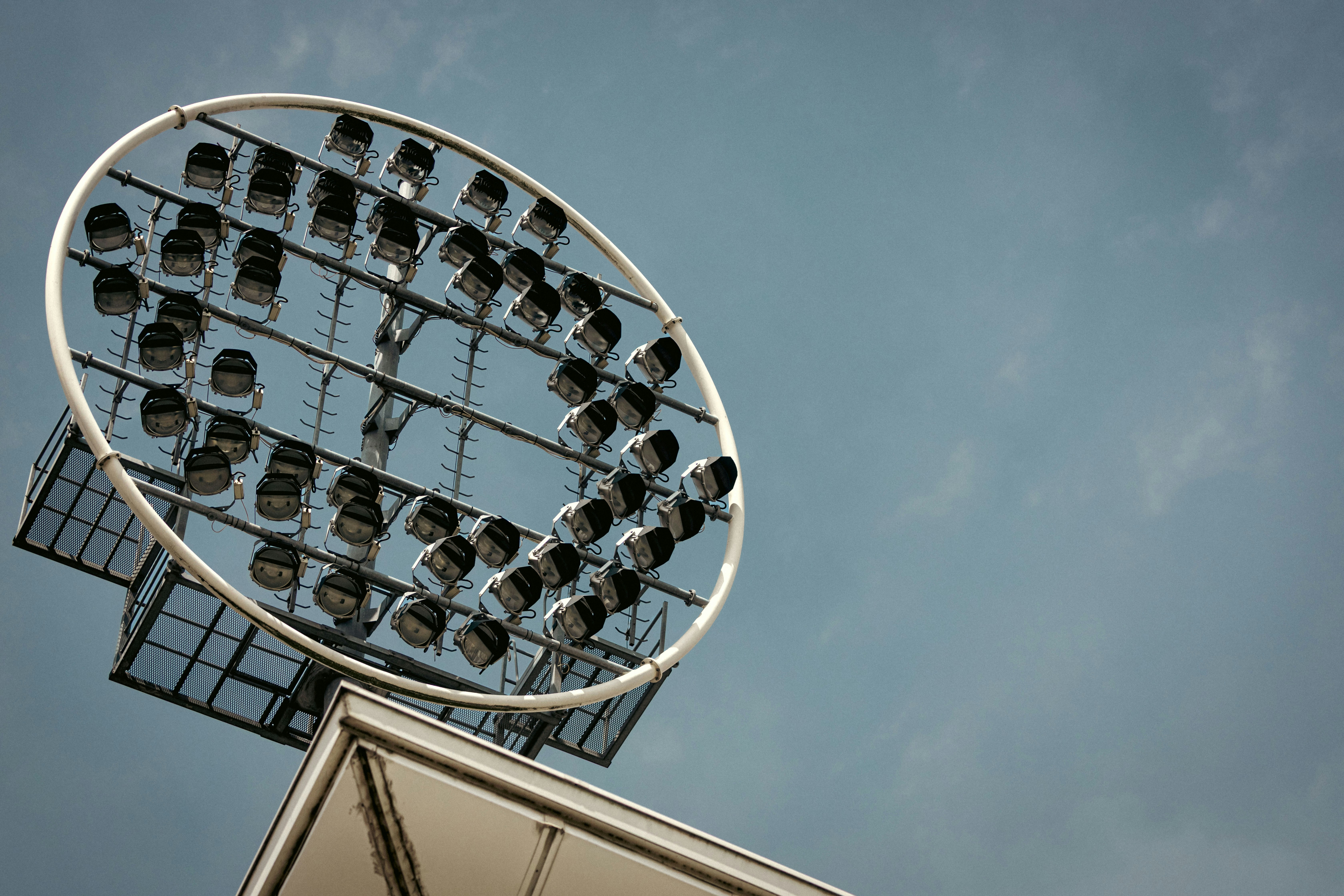 A circular stadium floodlight array against a clear blue sky