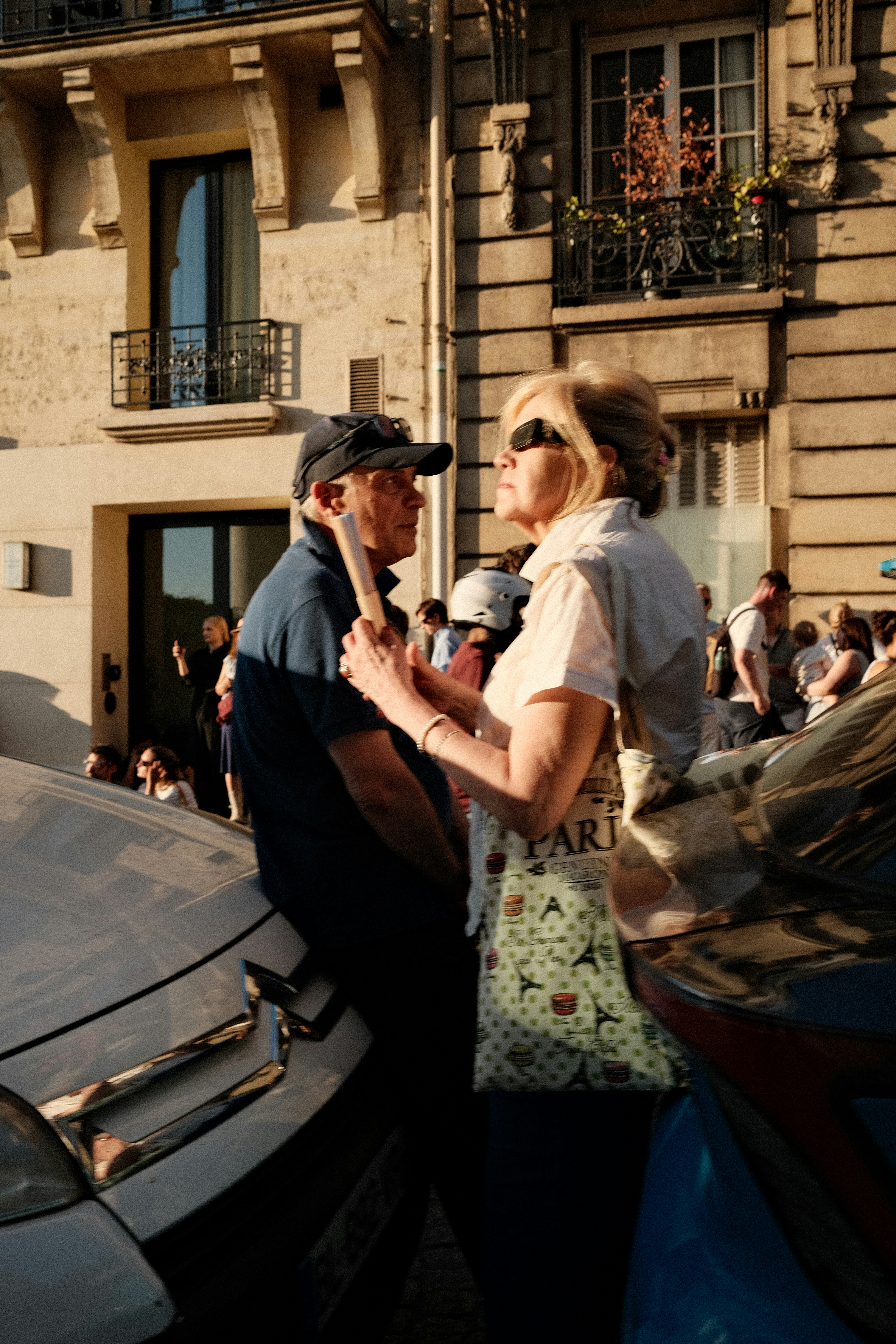 A man and a woman standing by a car on a street in Paris.