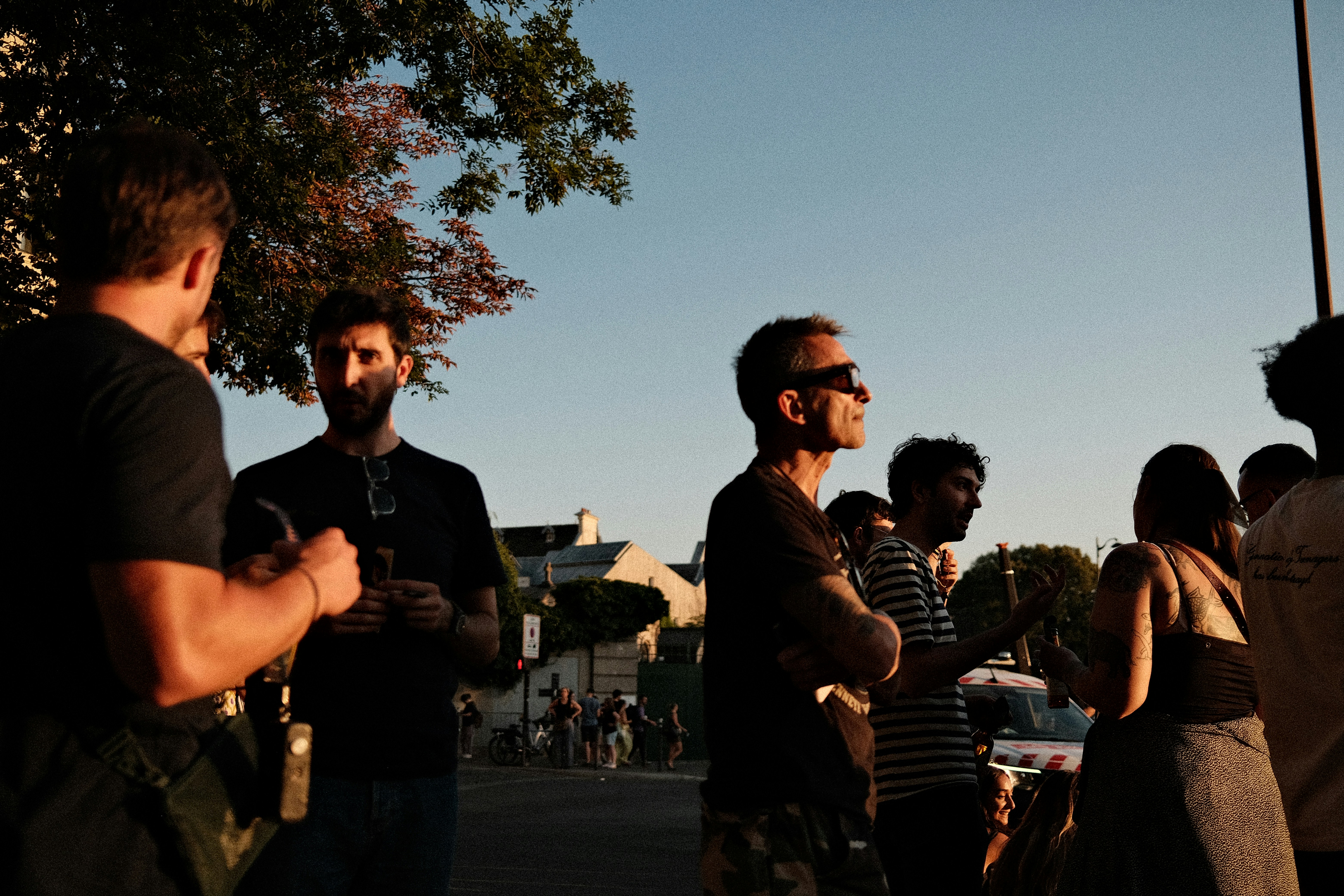 A group of people socializing outdoors in the warm light of late afternoon