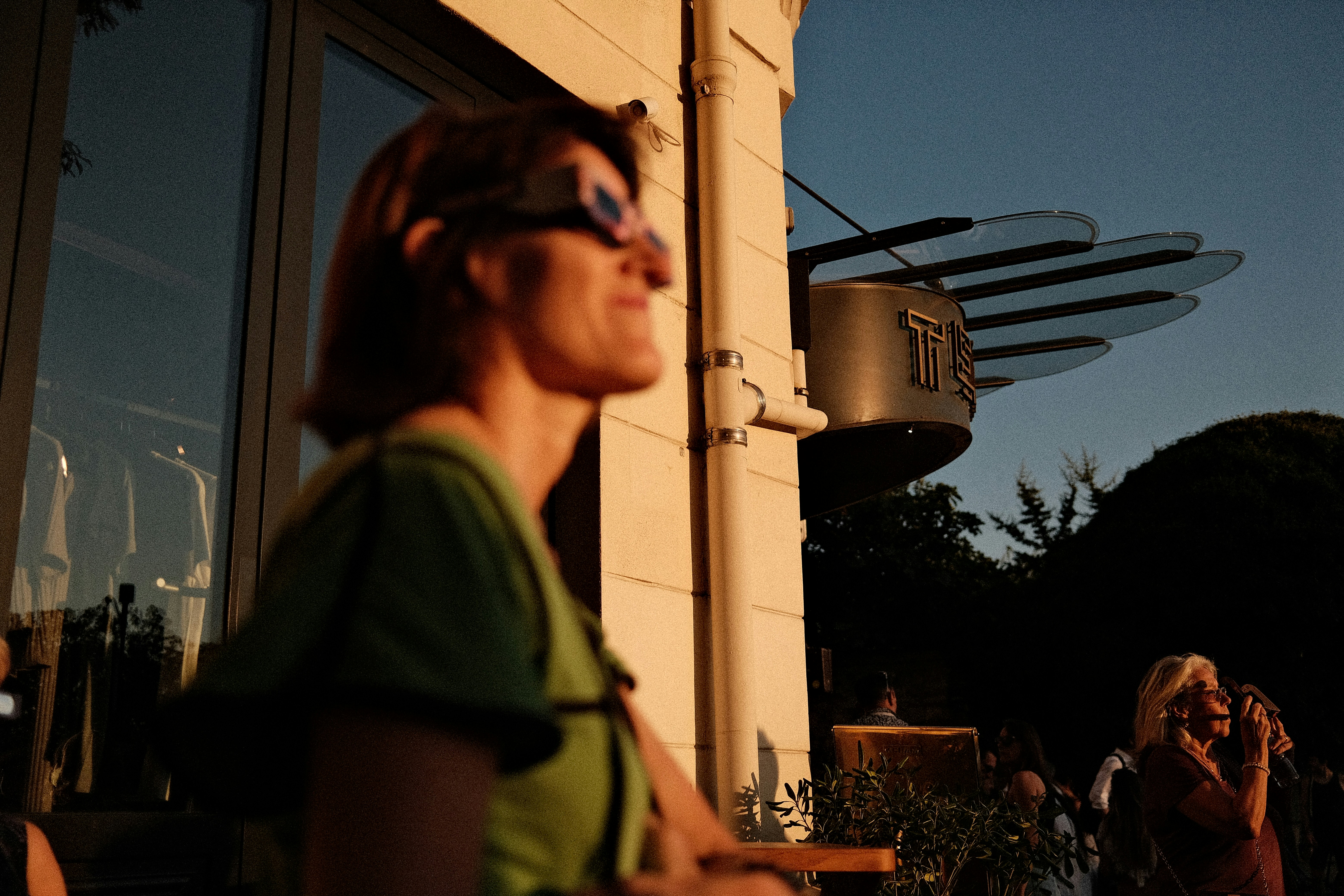 A person in a green shirt standing outside a building during golden hour.