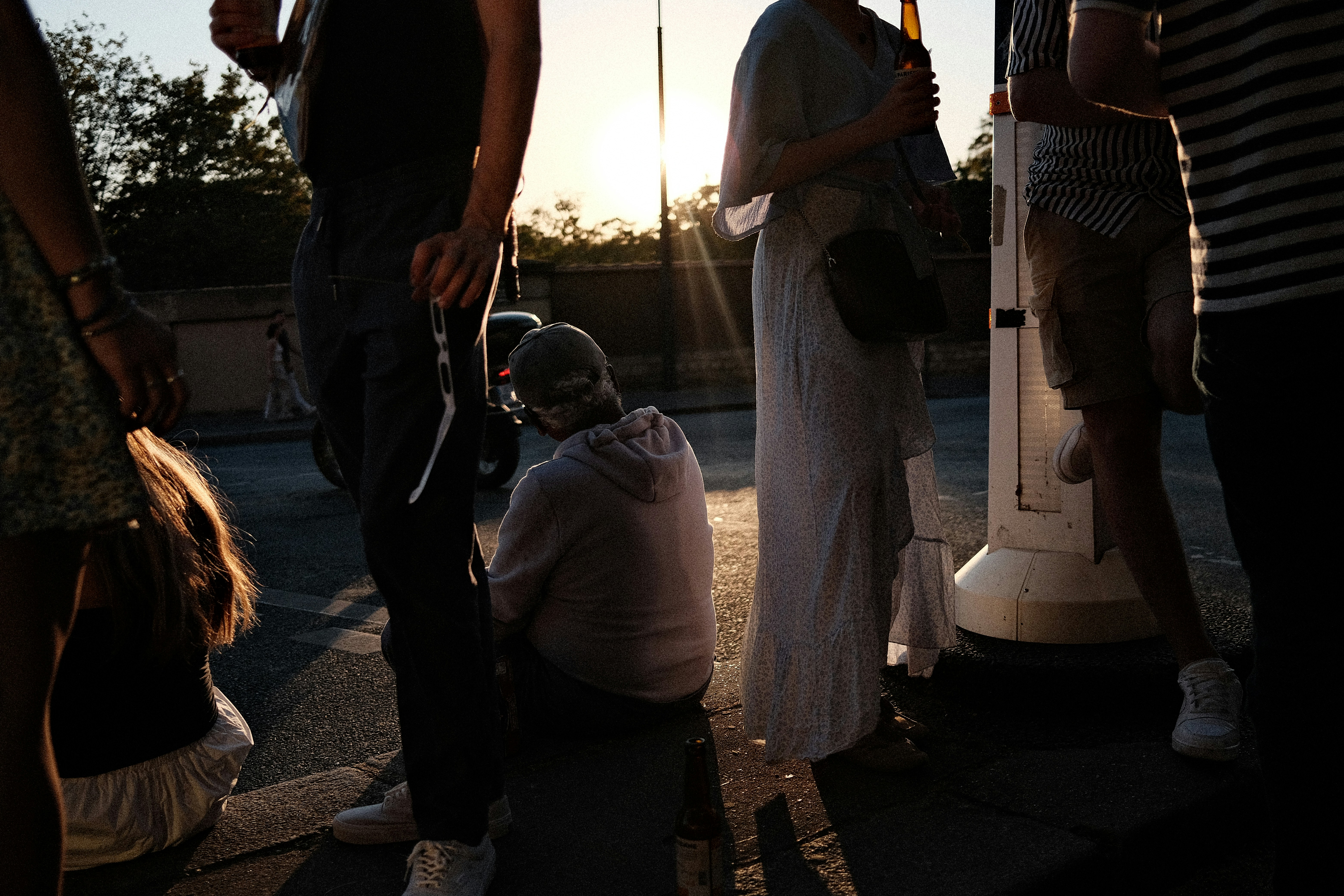 A group of people gathered on a street during the golden hour