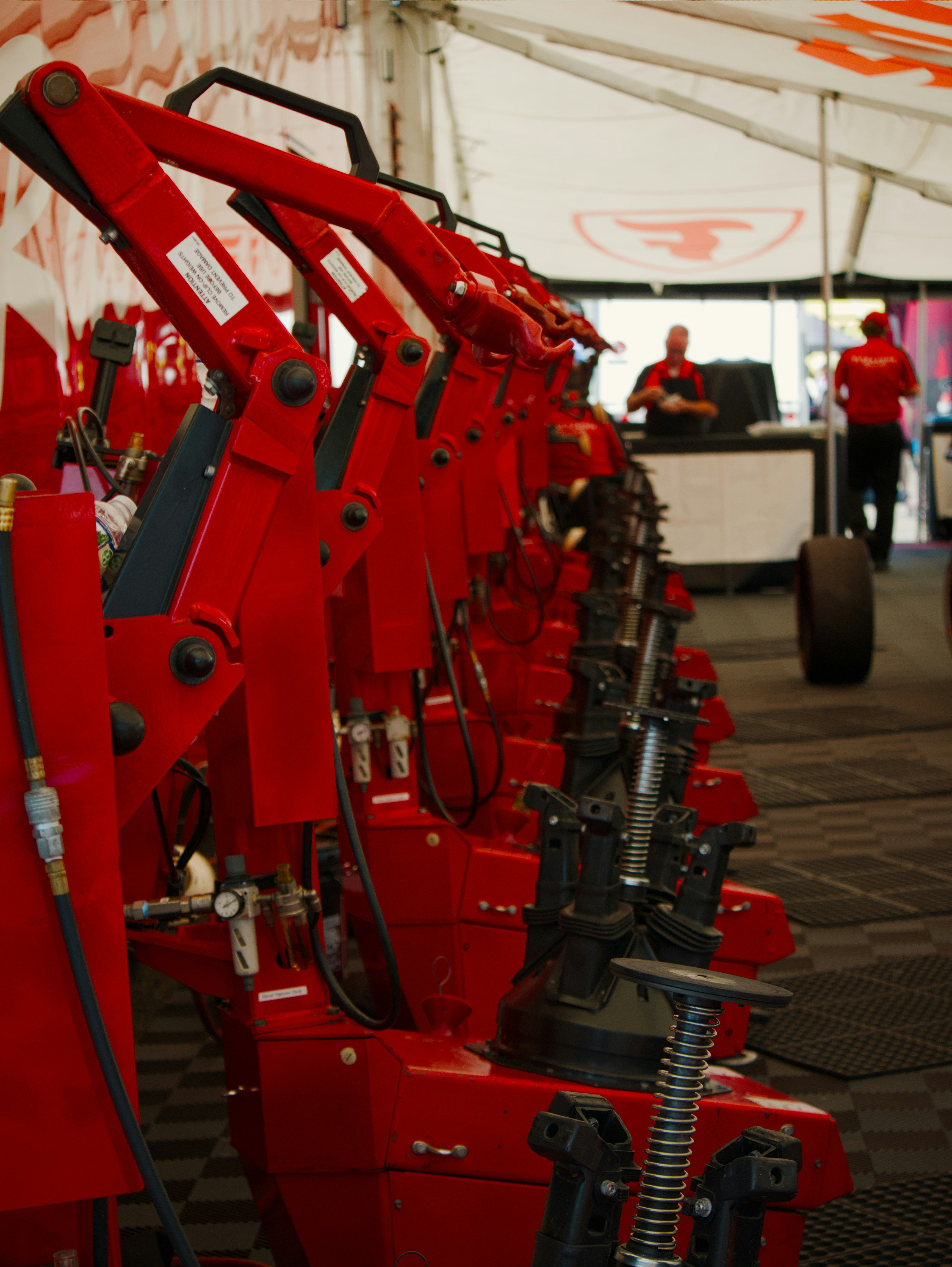 A row of red pneumatic tire changing machines inside a race team garage