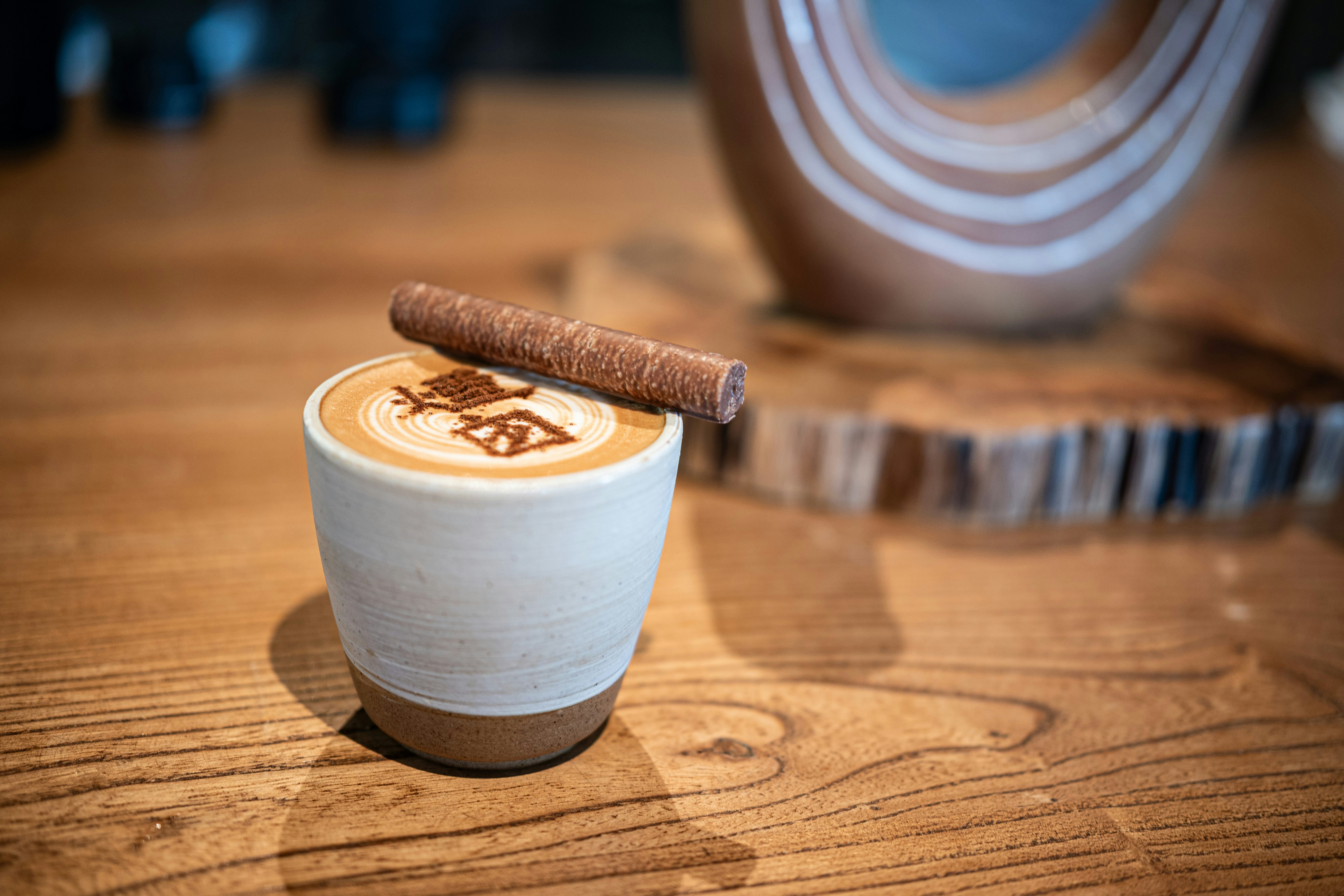 Latte with art and a chocolate stick on timber