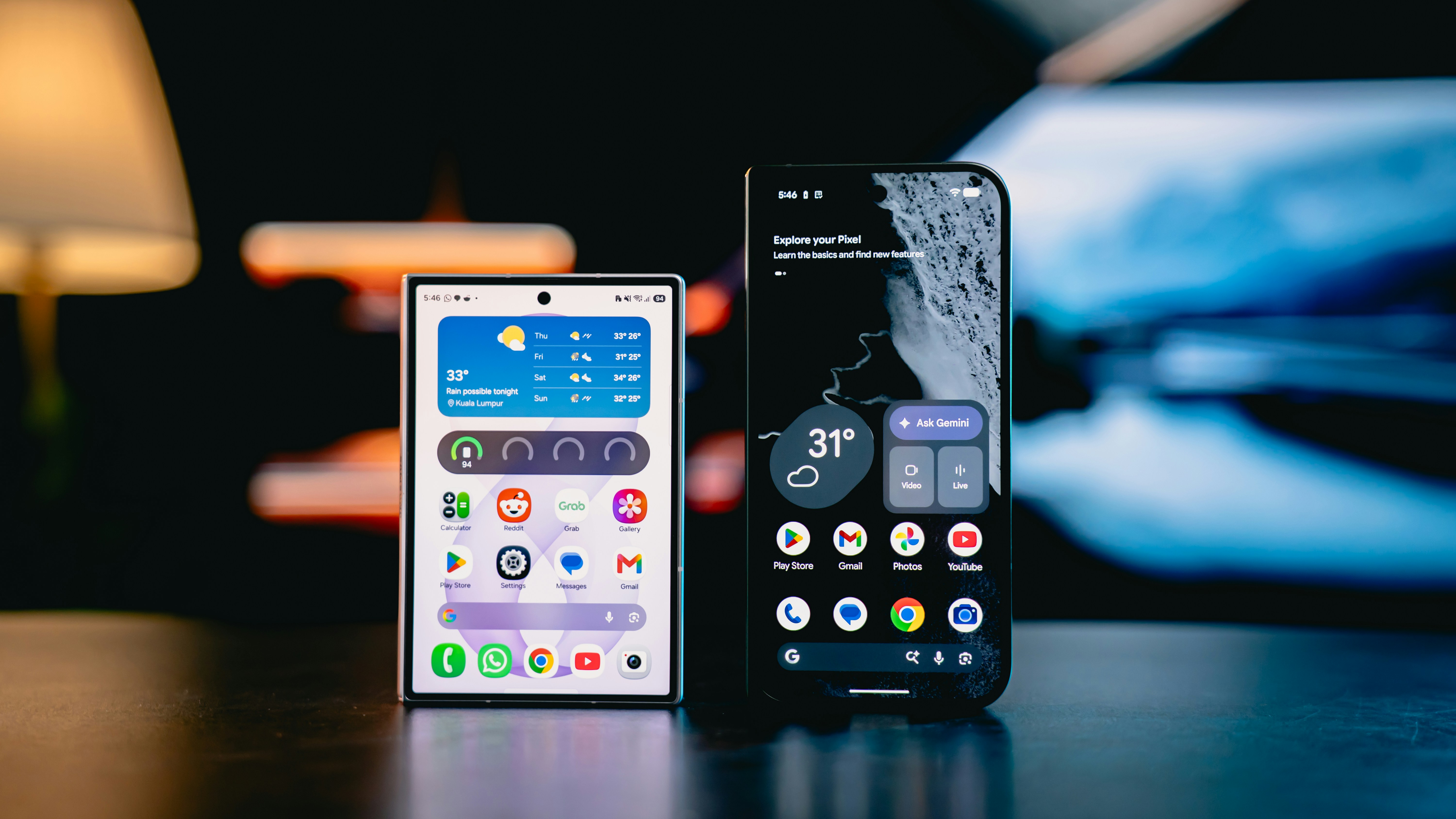 Two smartphones with illuminated screens on a dark surface in a dimly lit room
