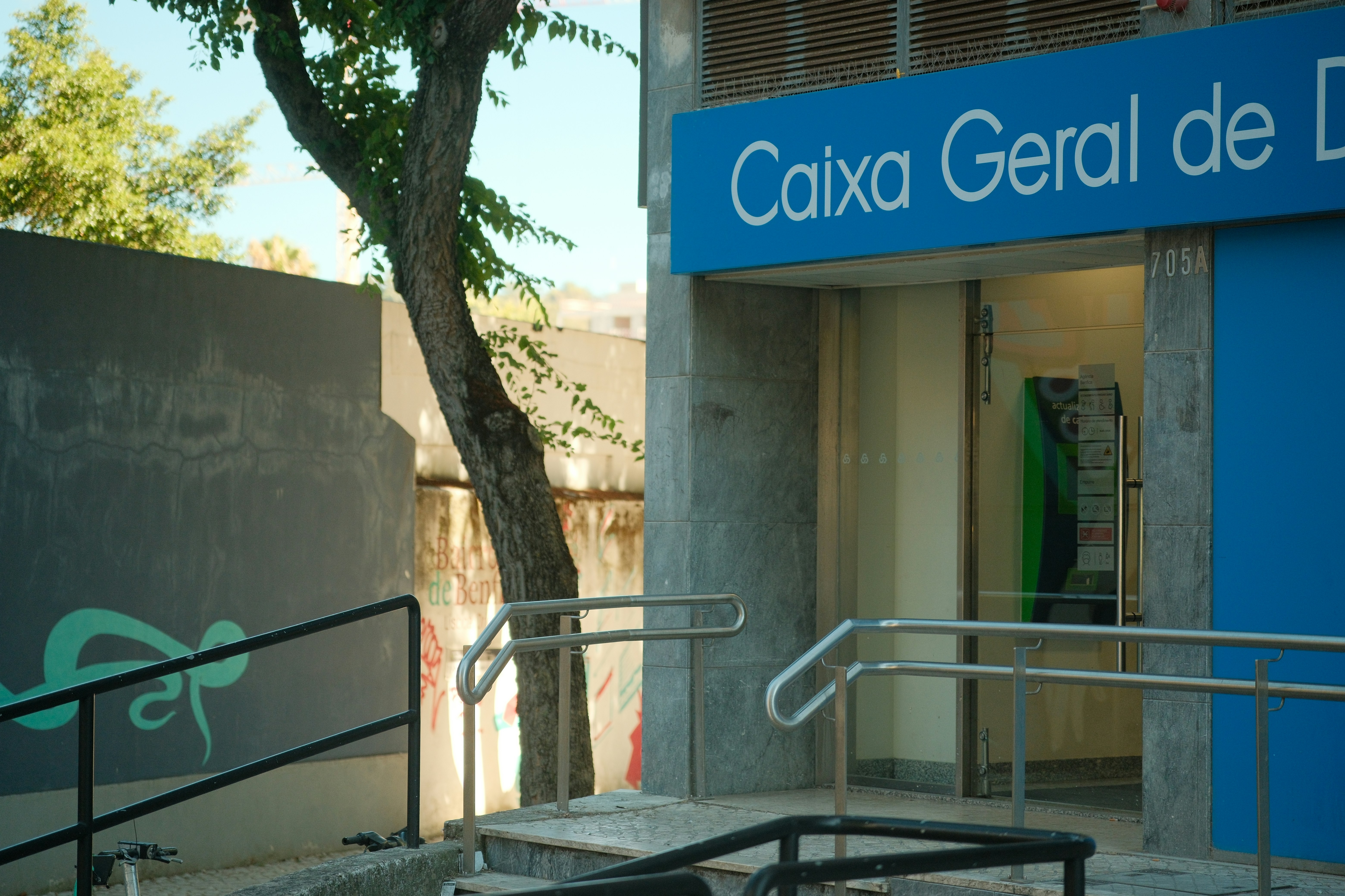 A Caixa Geral de Depósitos bank entrance with metal railings and a tree