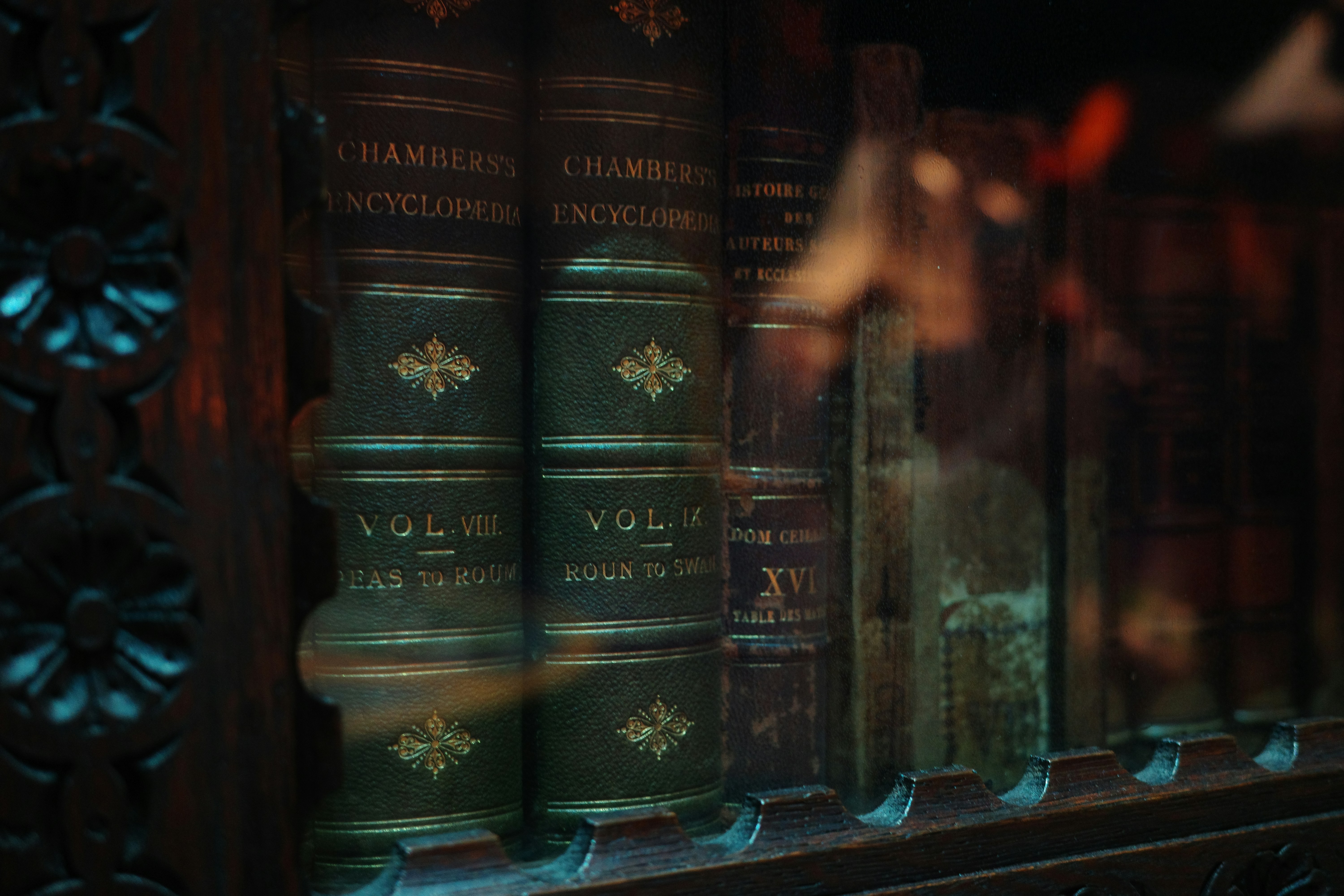 Antique leather-bound encyclopedias with gold lettering behind a glass cabinet door