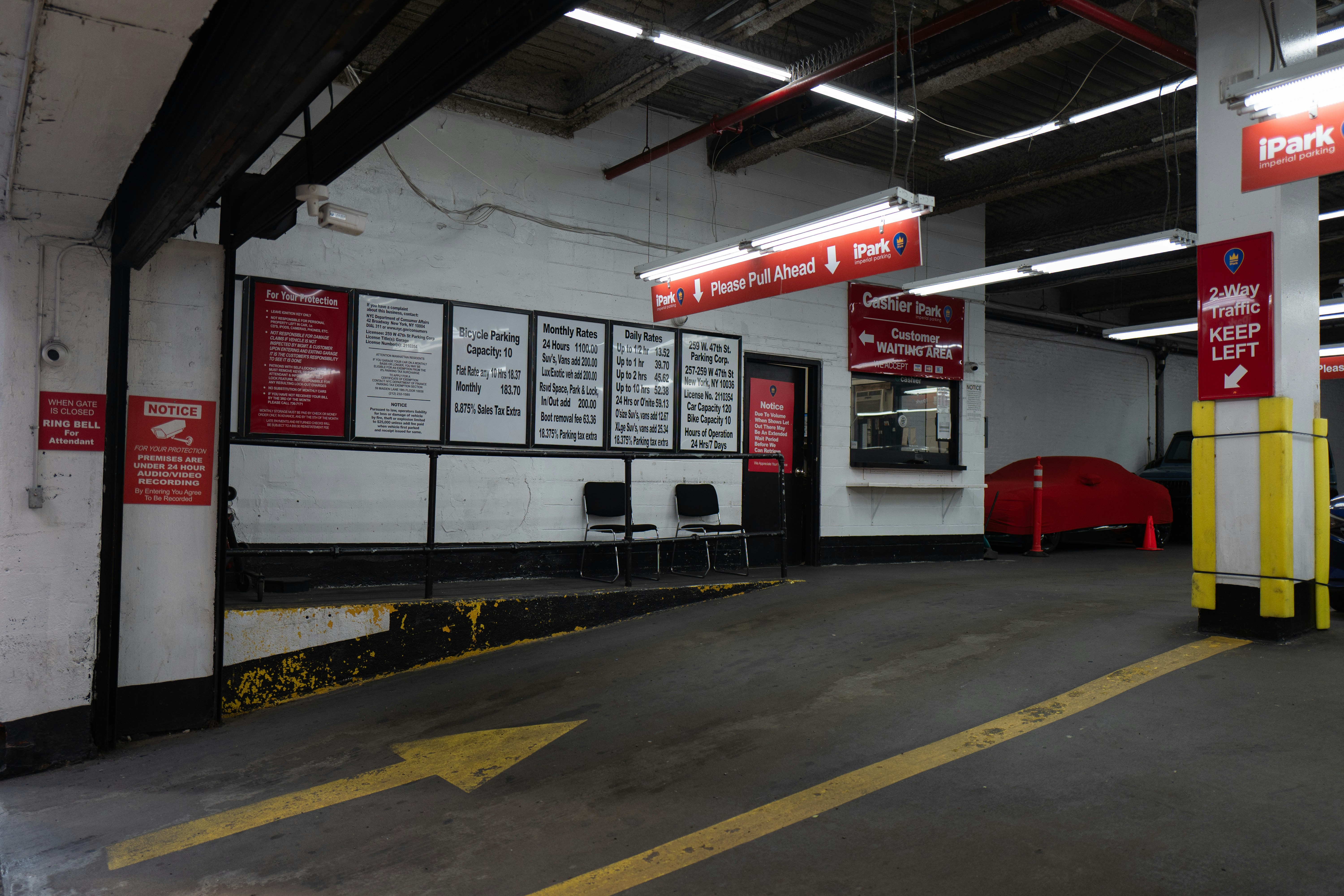 An indoor parking garage entrance with signage, a ramp, and a car cover