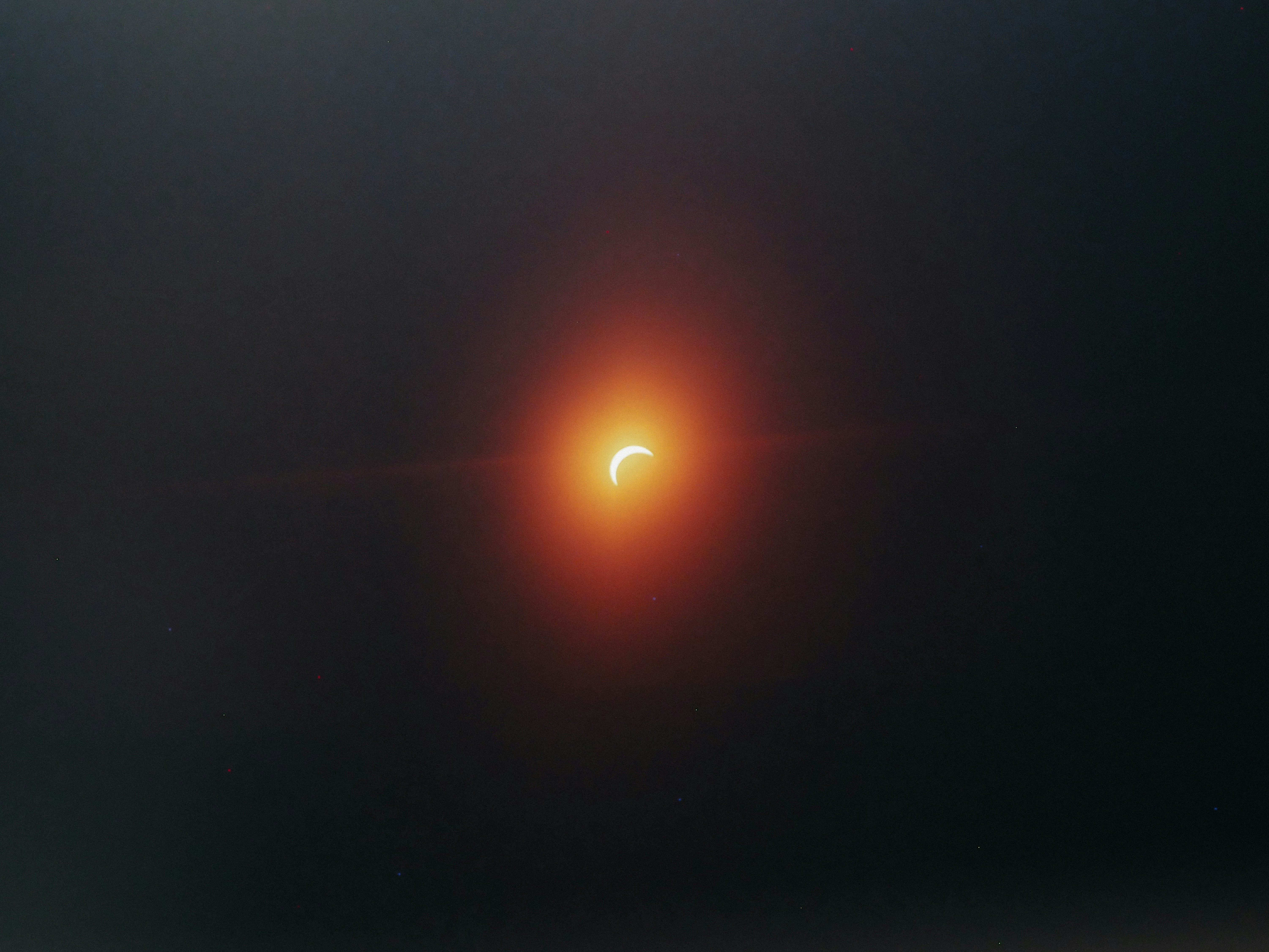 A crescent sun partially eclipsed by the moon against a dark sky