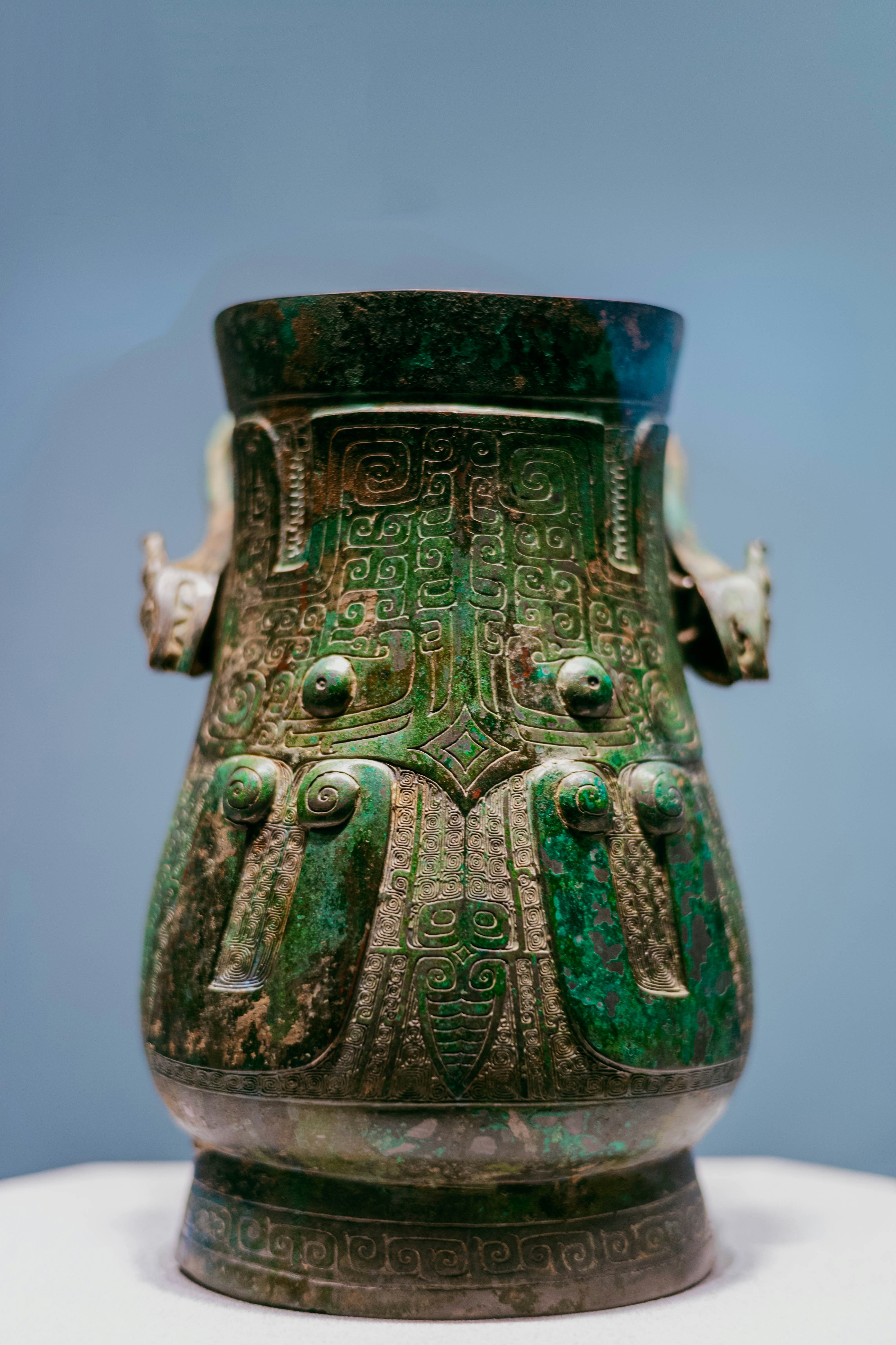 An ancient bronze vessel with intricate relief patterns and a green patina.