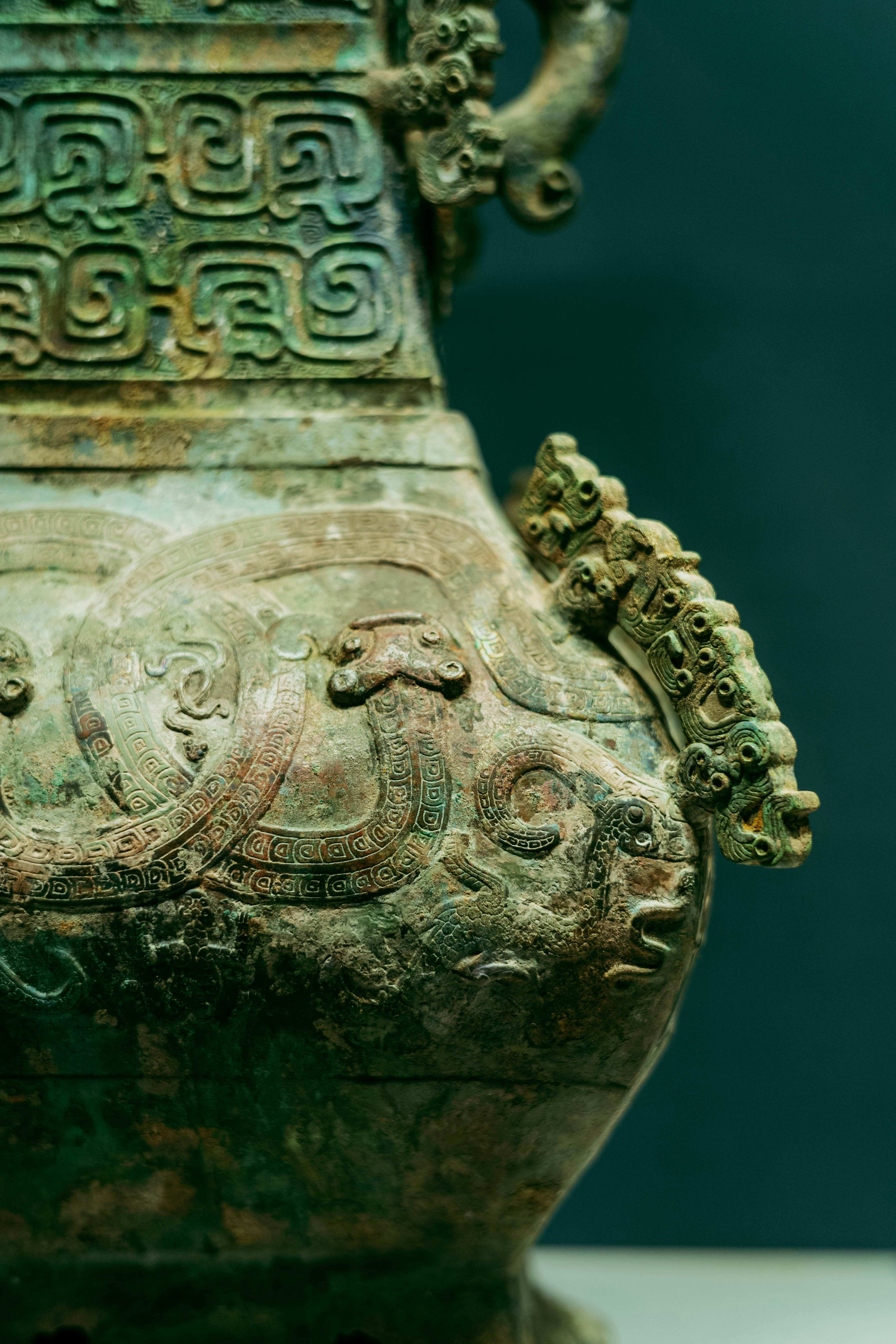 An ancient bronze vessel with intricate relief carvings of mythical creatures and geometric patterns.