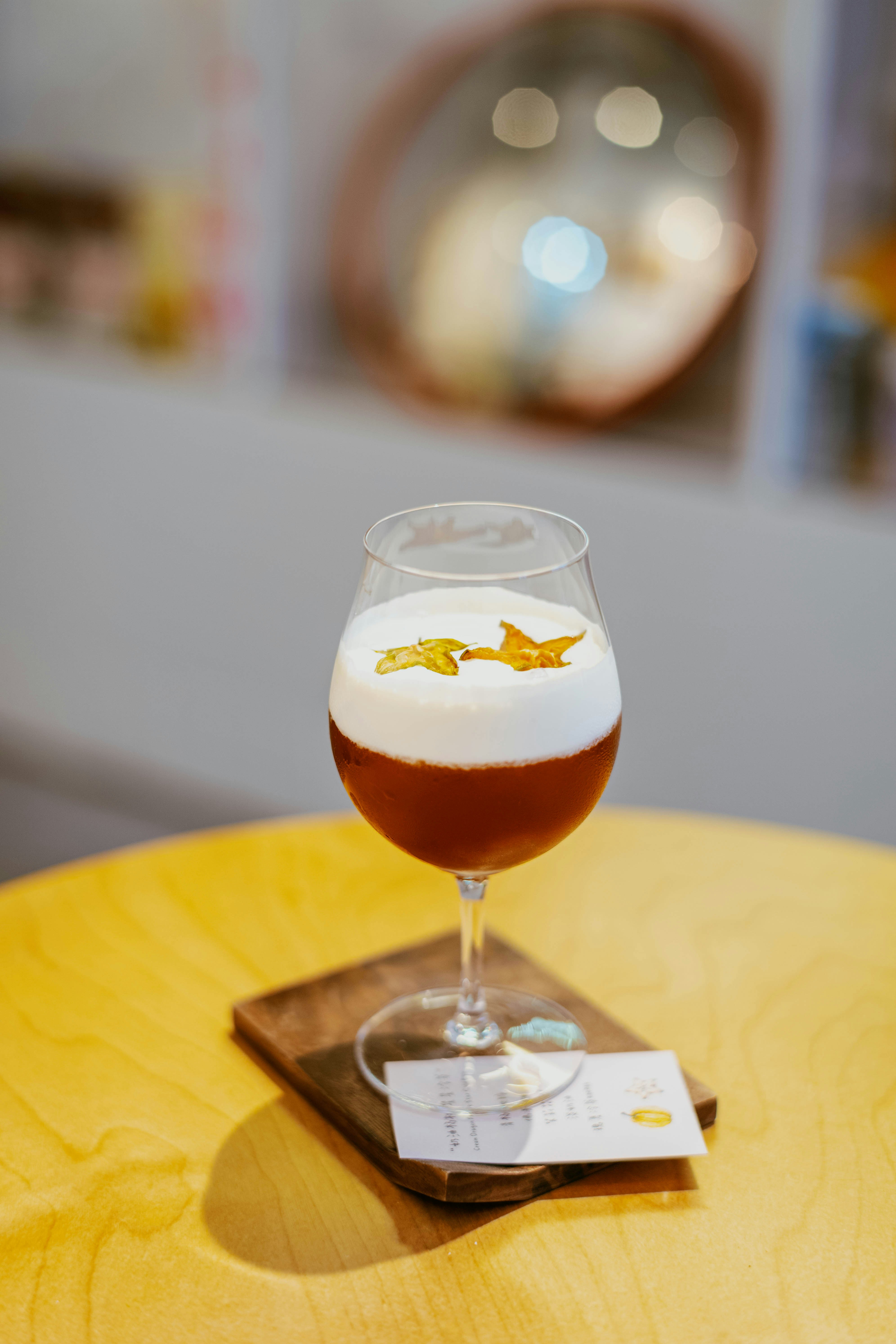 A cocktail topped with foam and star fruit slices on a wooden coaster.
