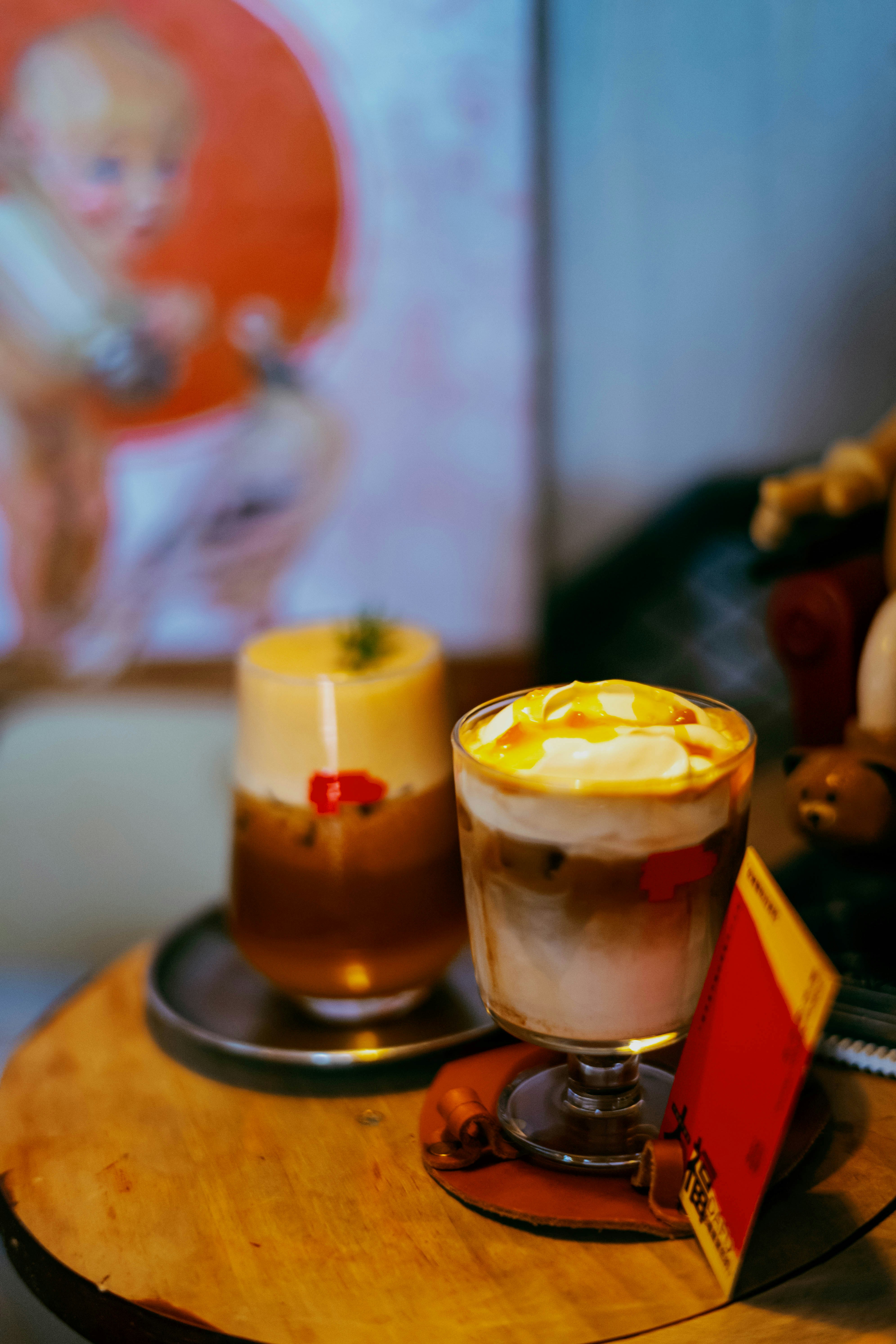 Two iced coffee drinks with cream and caramel drizzle on a wooden table.