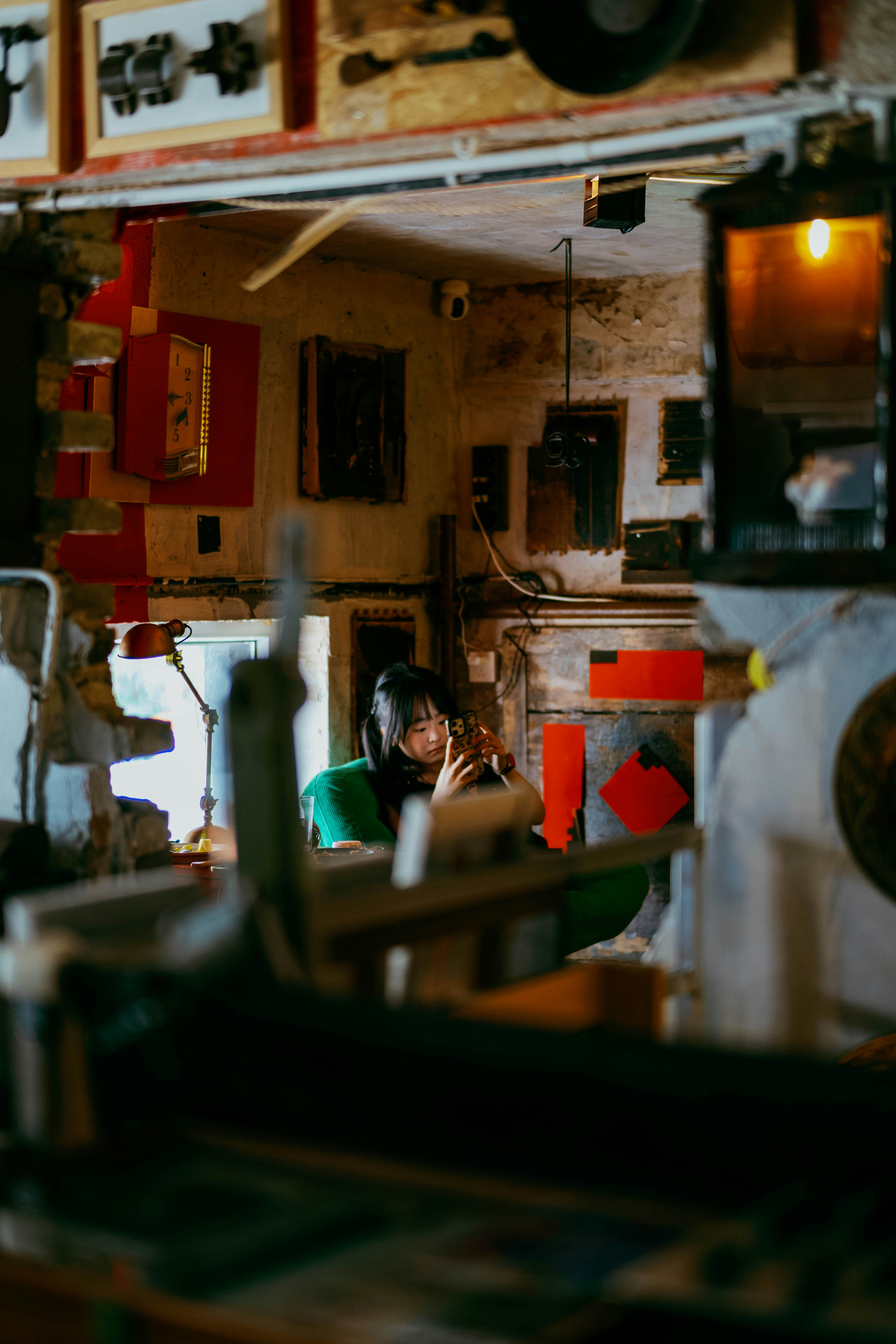 A person in a green sweater using a smartphone in a rustic room.