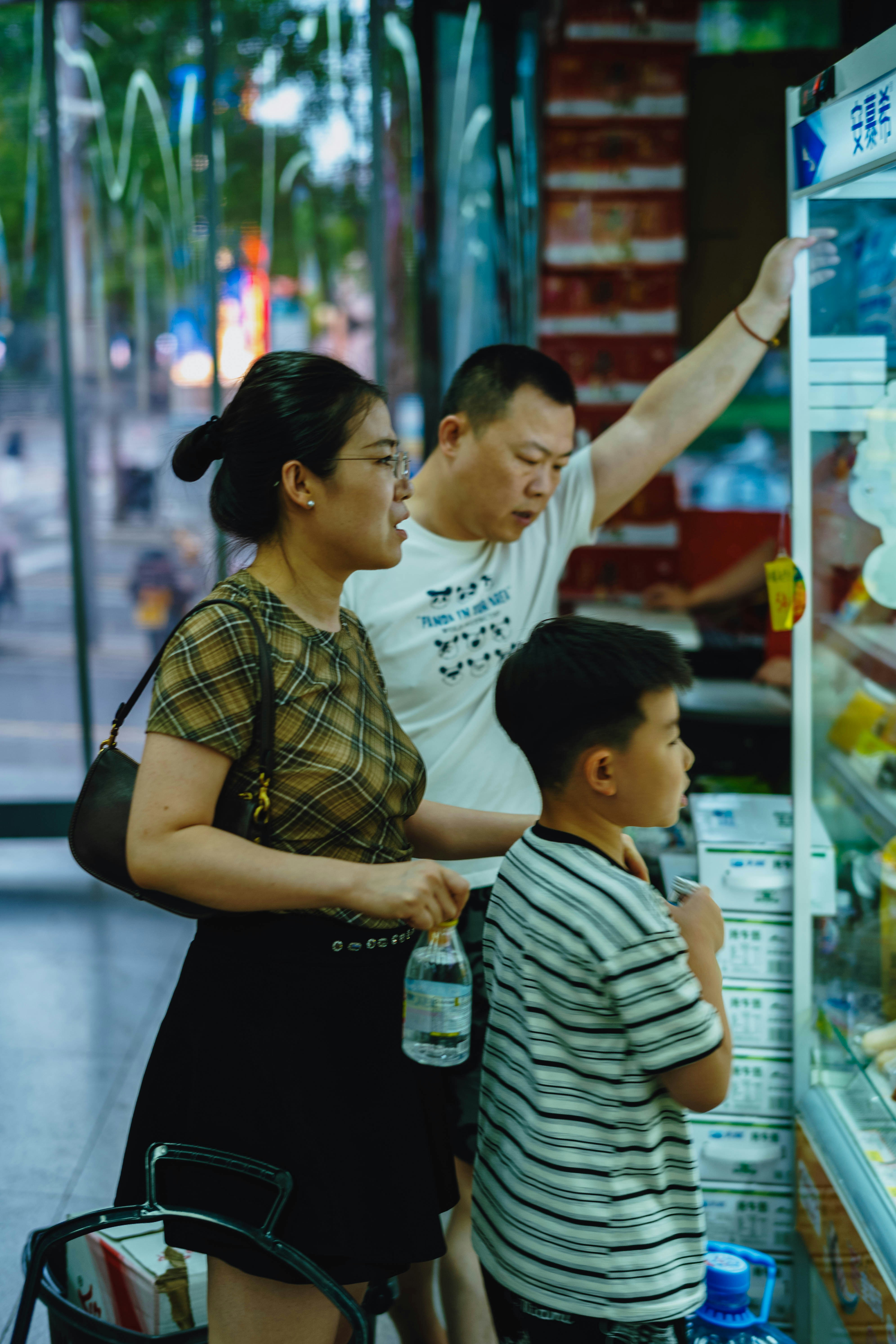 A woman, a man, and a child looking at a refrigerated display case.