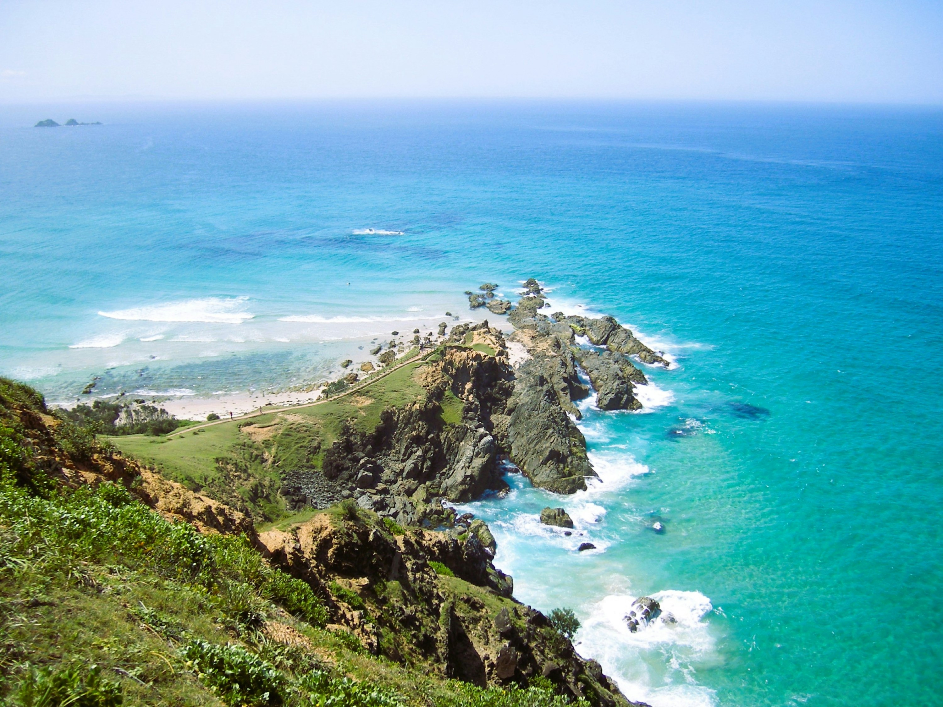 A rocky headland extending into turquoise ocean water under a clear blue sky