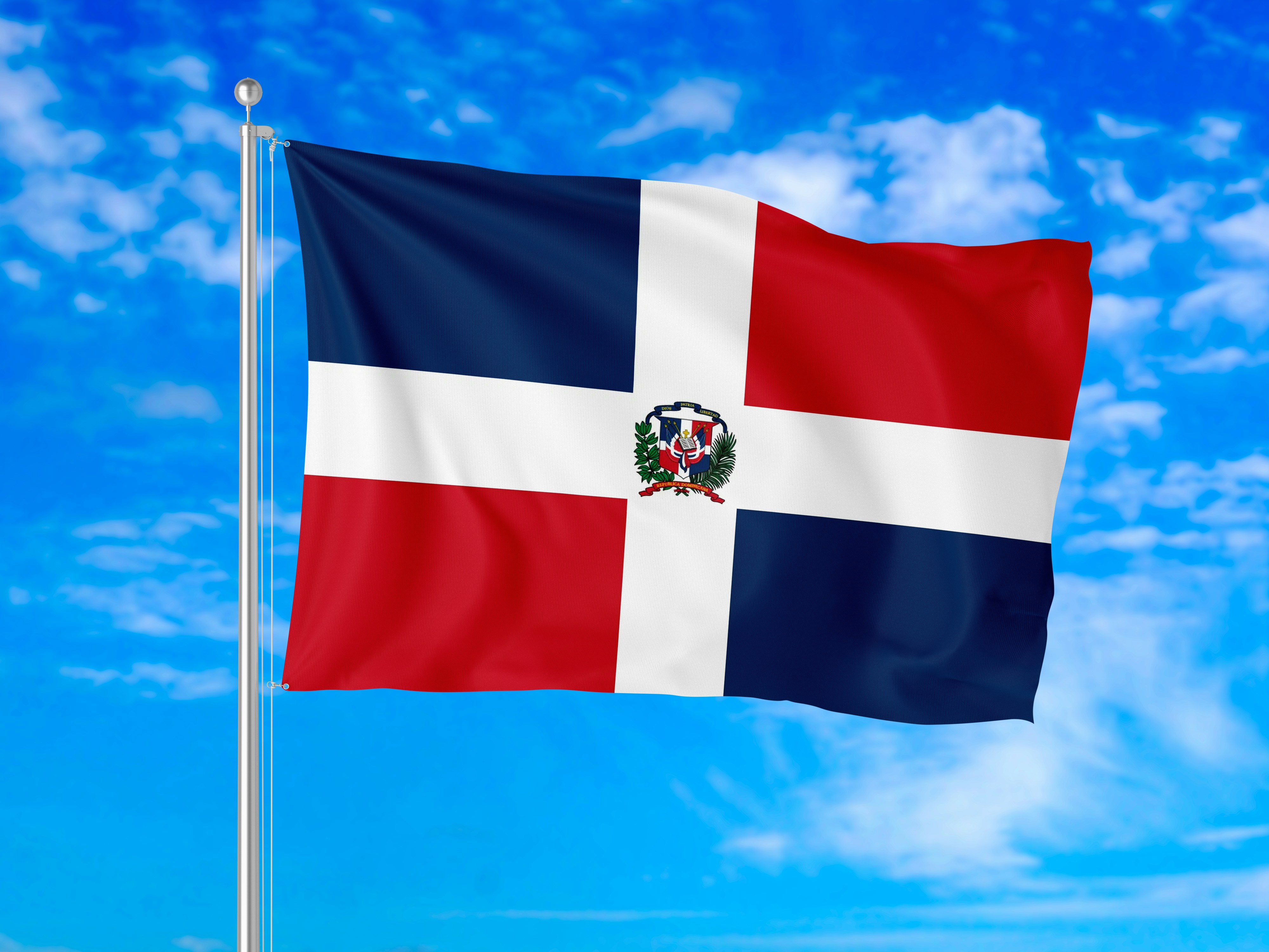 The flag of the Dominican Republic waving against a bright blue sky