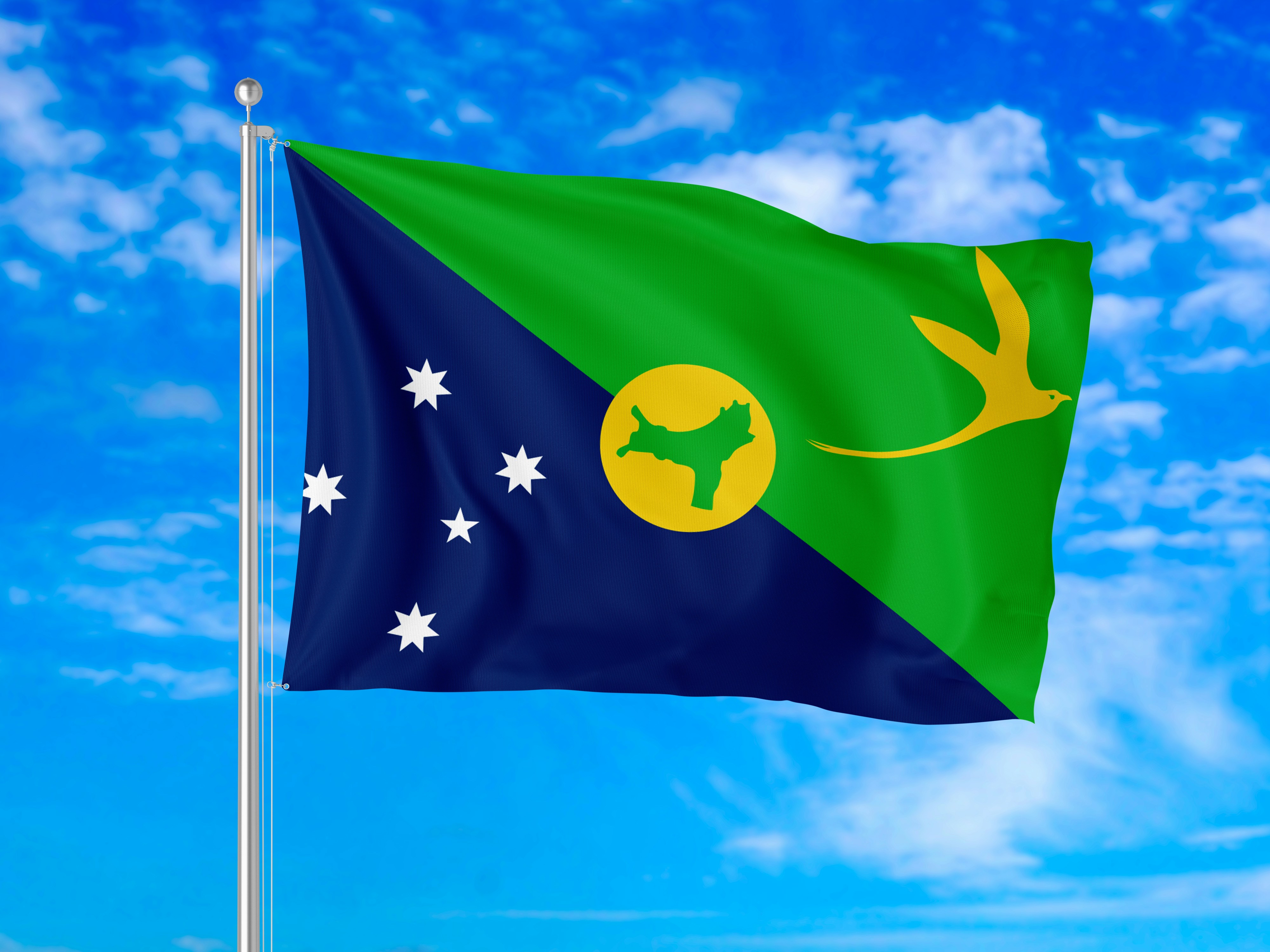 The flag of Christmas Island waving against a bright blue sky with clouds