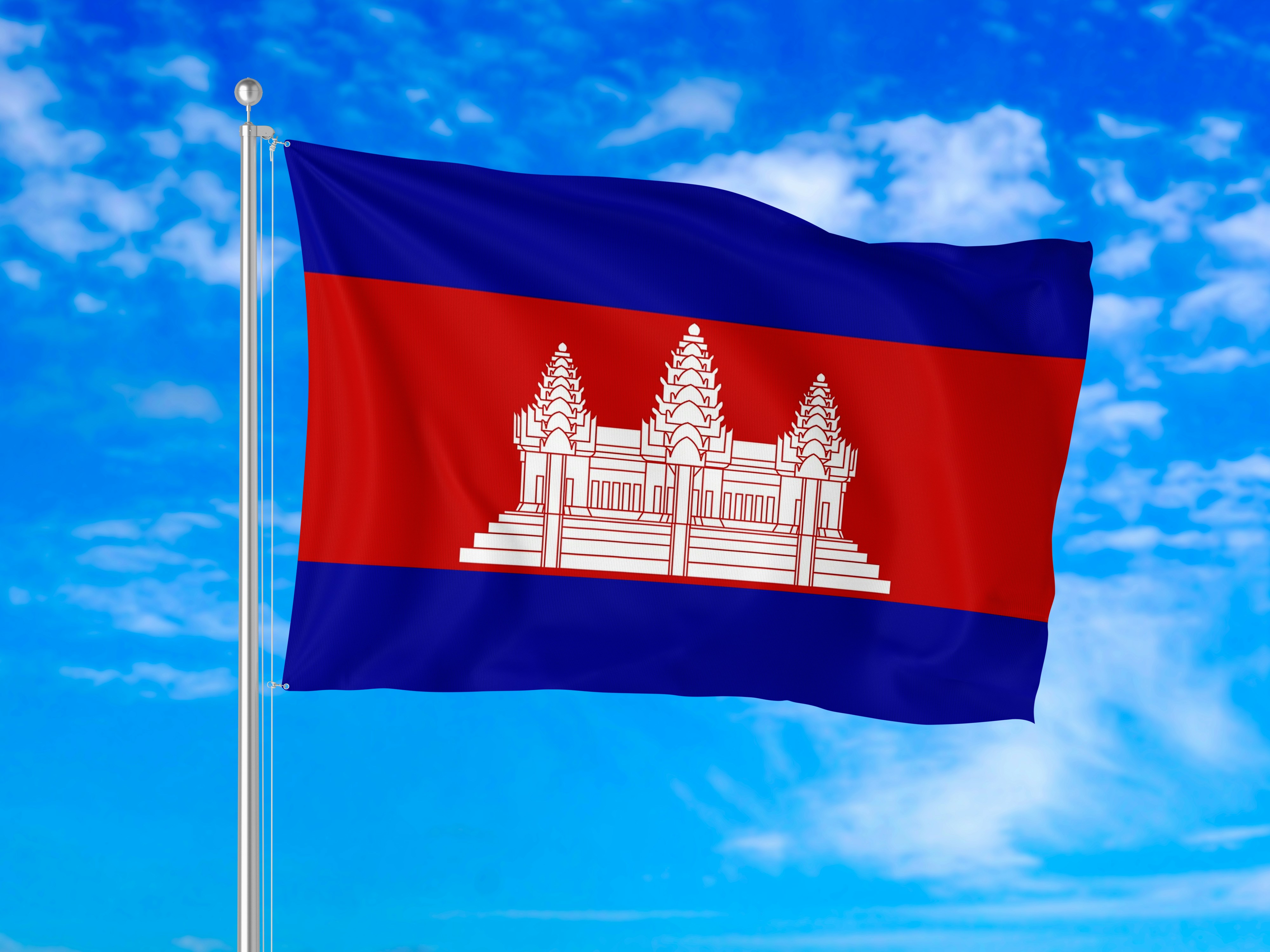 Die Flagge Kambodschas weht an einer Metallstange gegen einen blauen Himmel