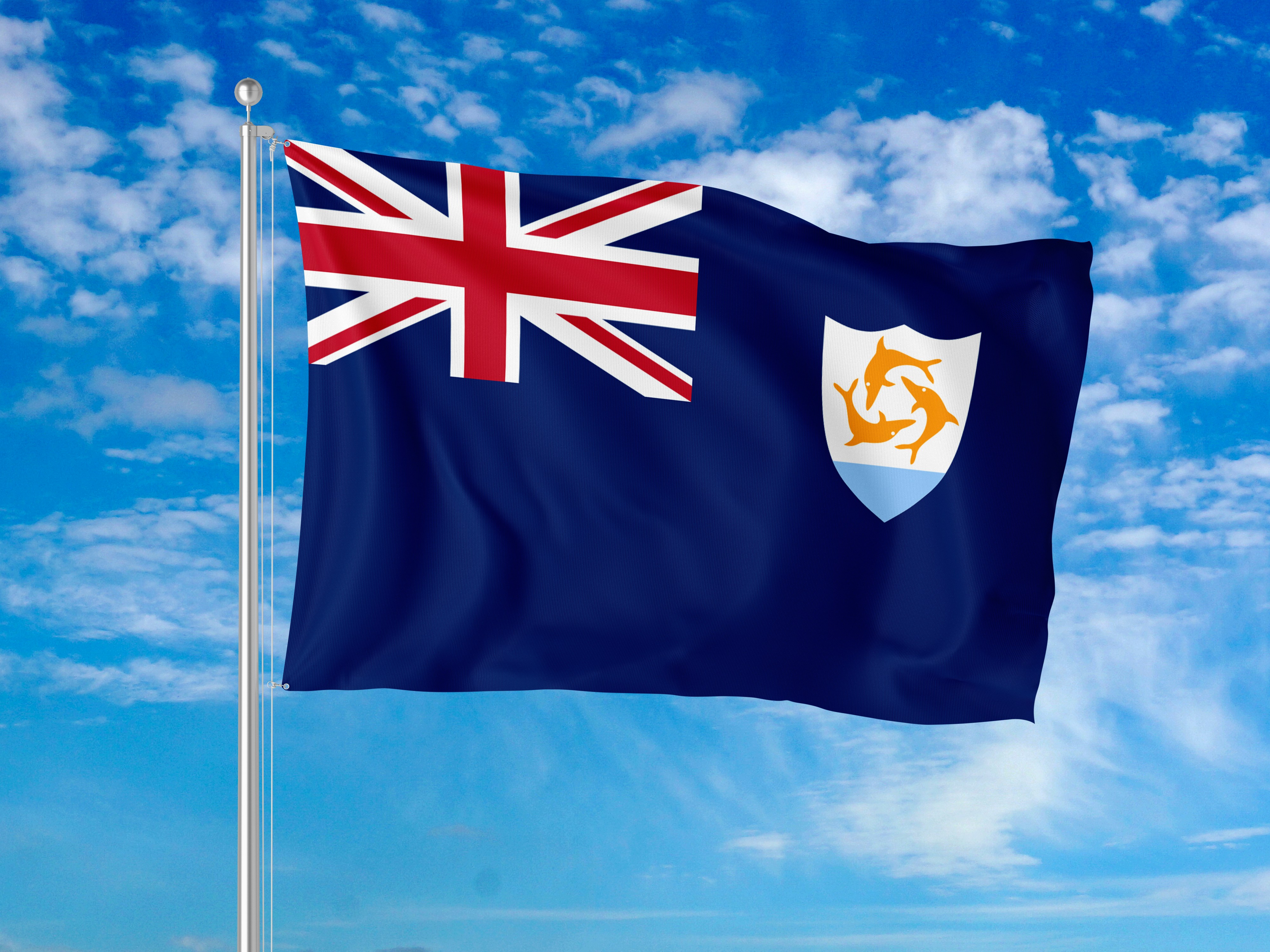 Le drapeau d’Anguilla flottant sur un poteau métallique contre un ciel bleu