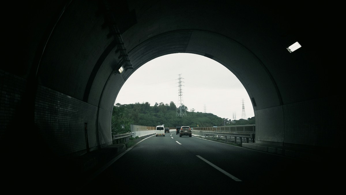Cars emerging from a tunnel onto an open stretch of road