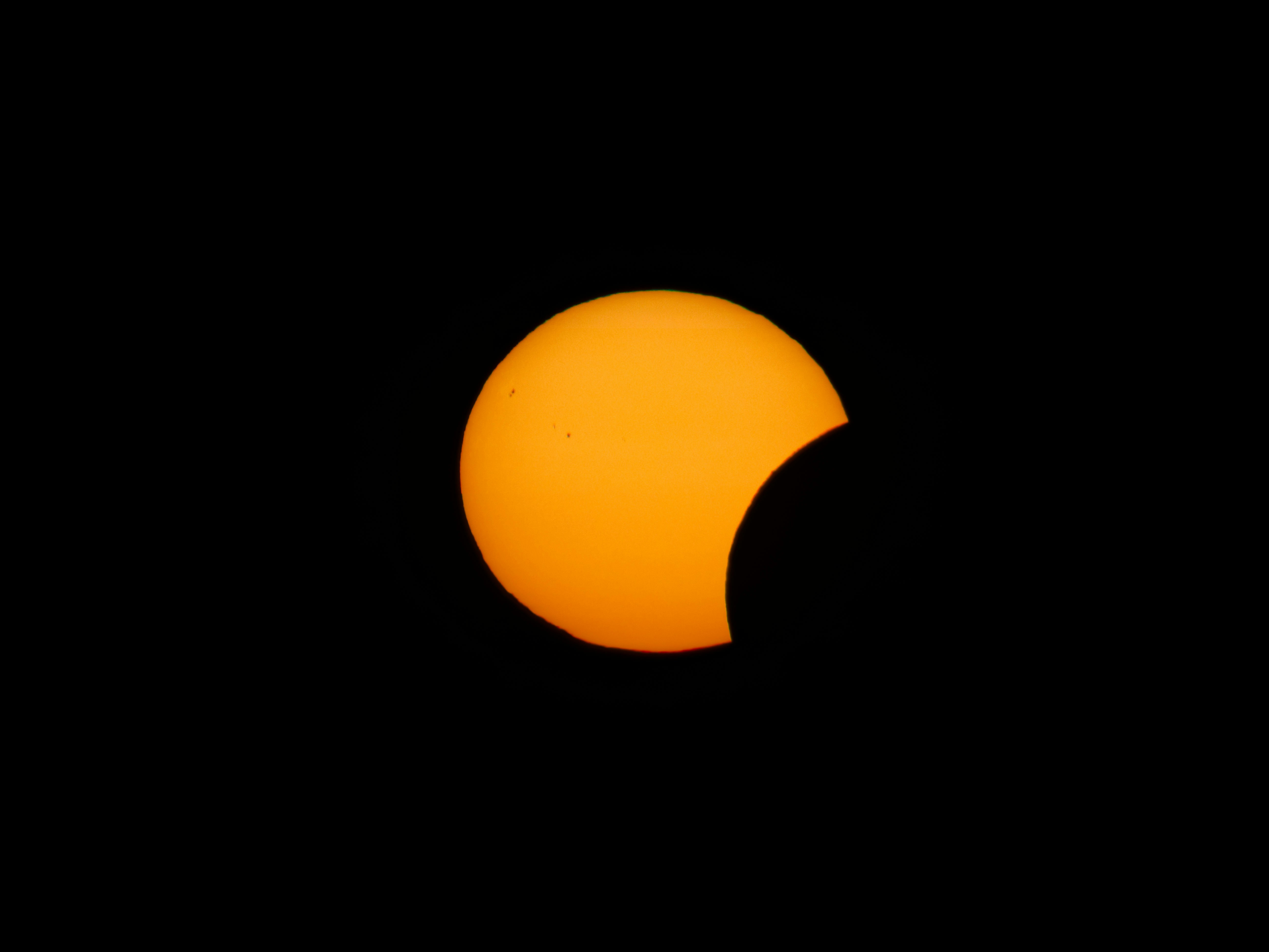 A partial solar eclipse with the moon obscuring part of the bright sun.