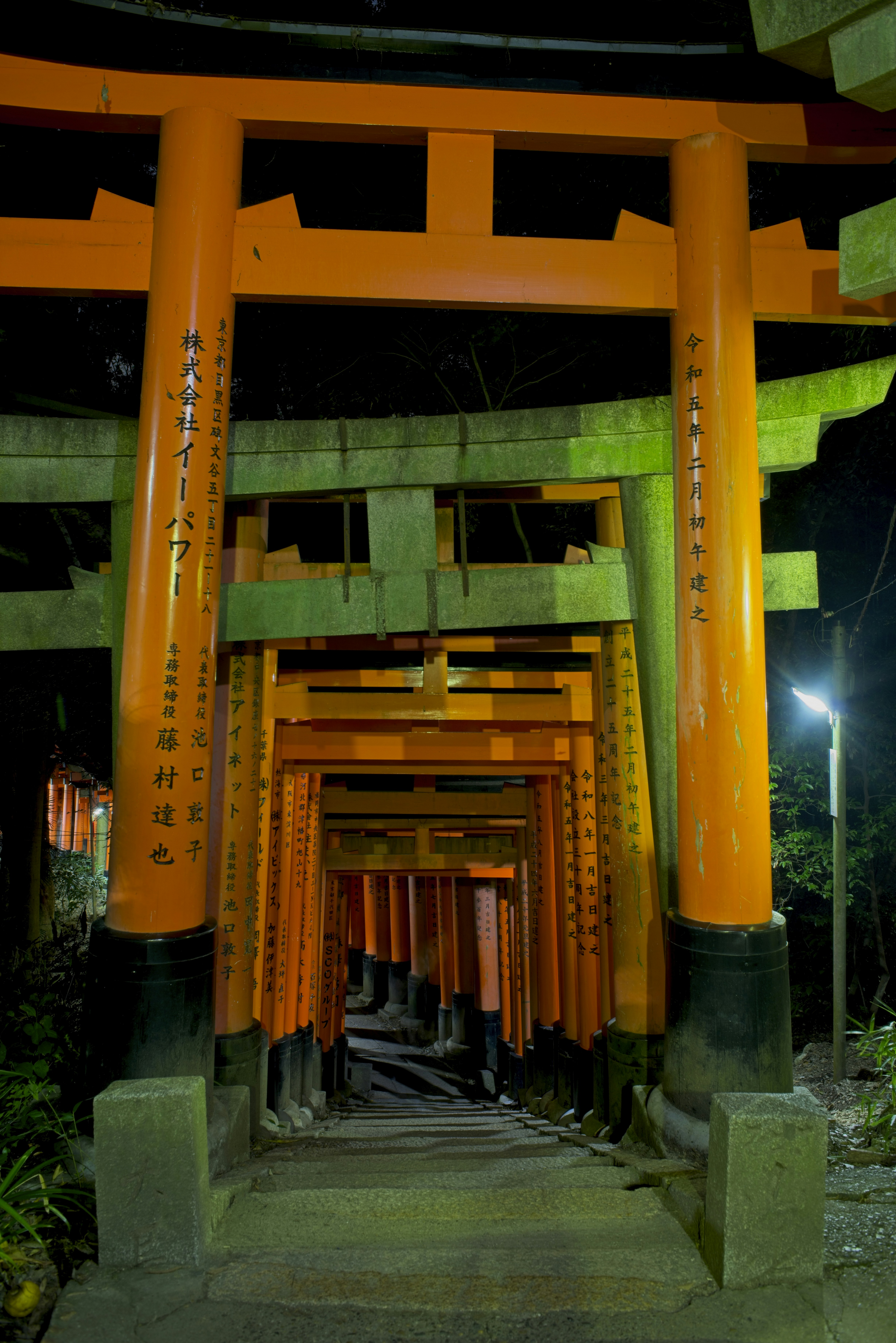 Un camino a través de las puertas torii naranjas en el Santuario Fushimi Inari en Kioto por la noche.