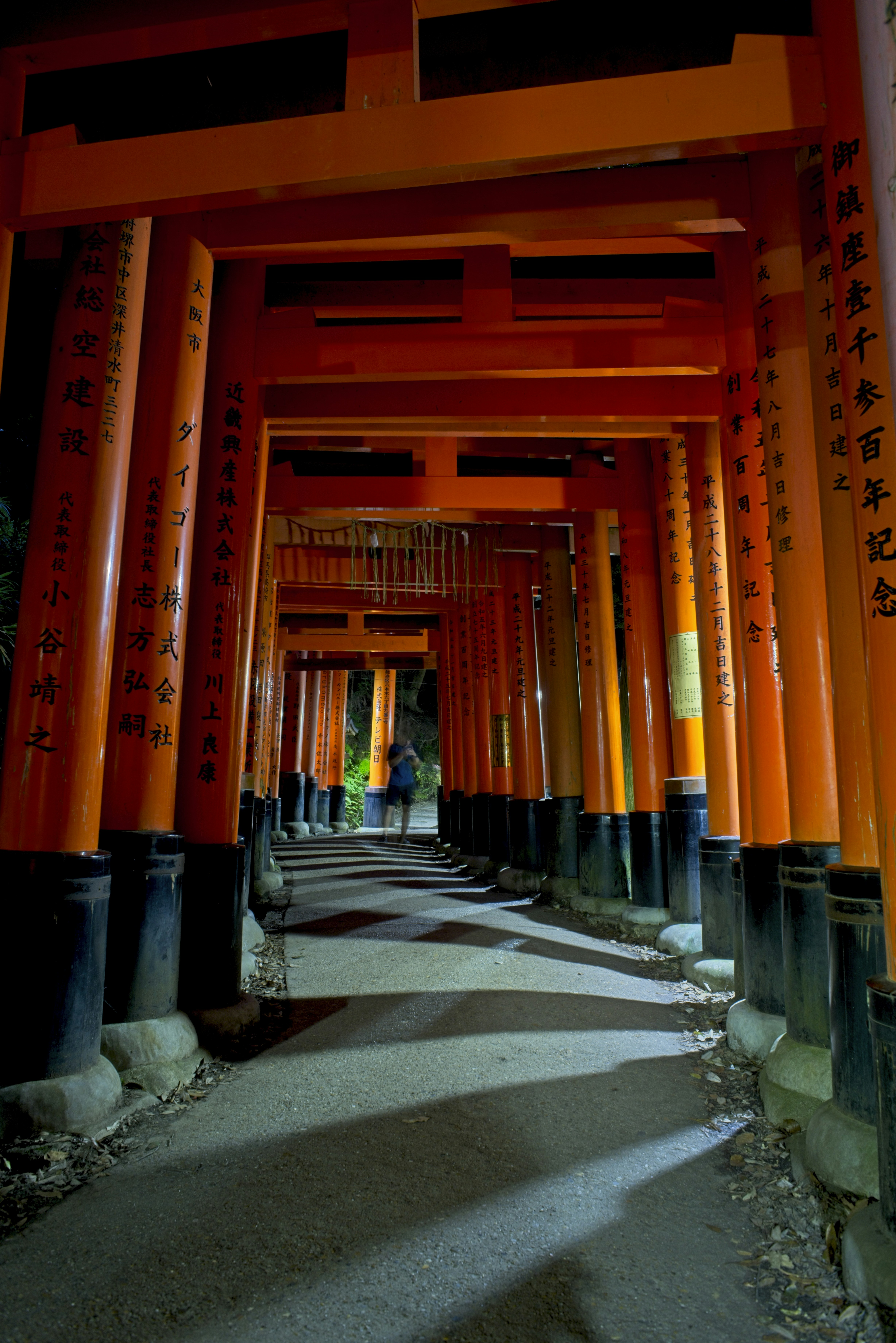 Una persona caminando por un camino de torii naranjas en el Santuario Fushimi Inari.
