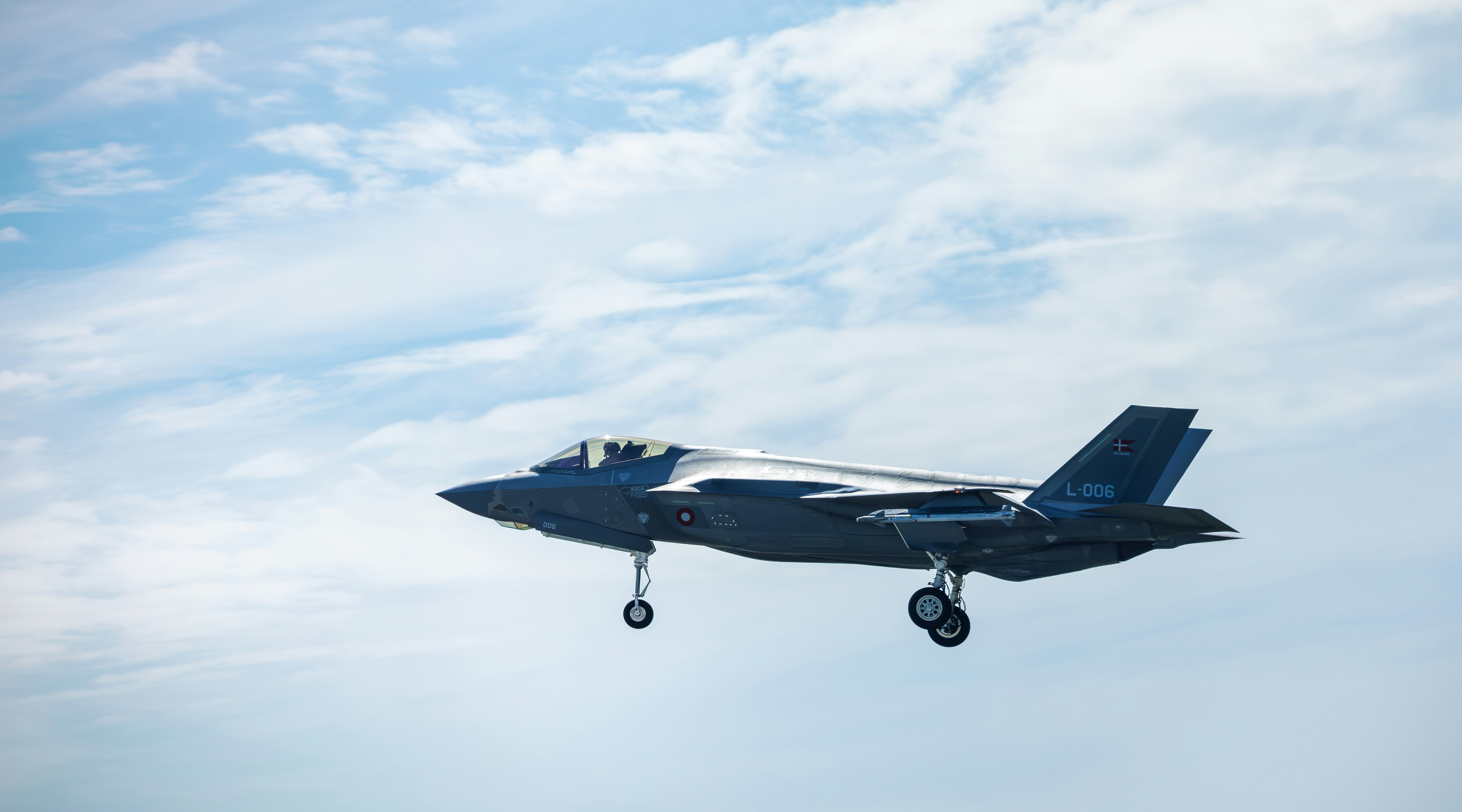 Ein grauer F-35-Kampfjet mit Fahrwerk, das gegen einen bewölkten Himmel ausgefahren ist