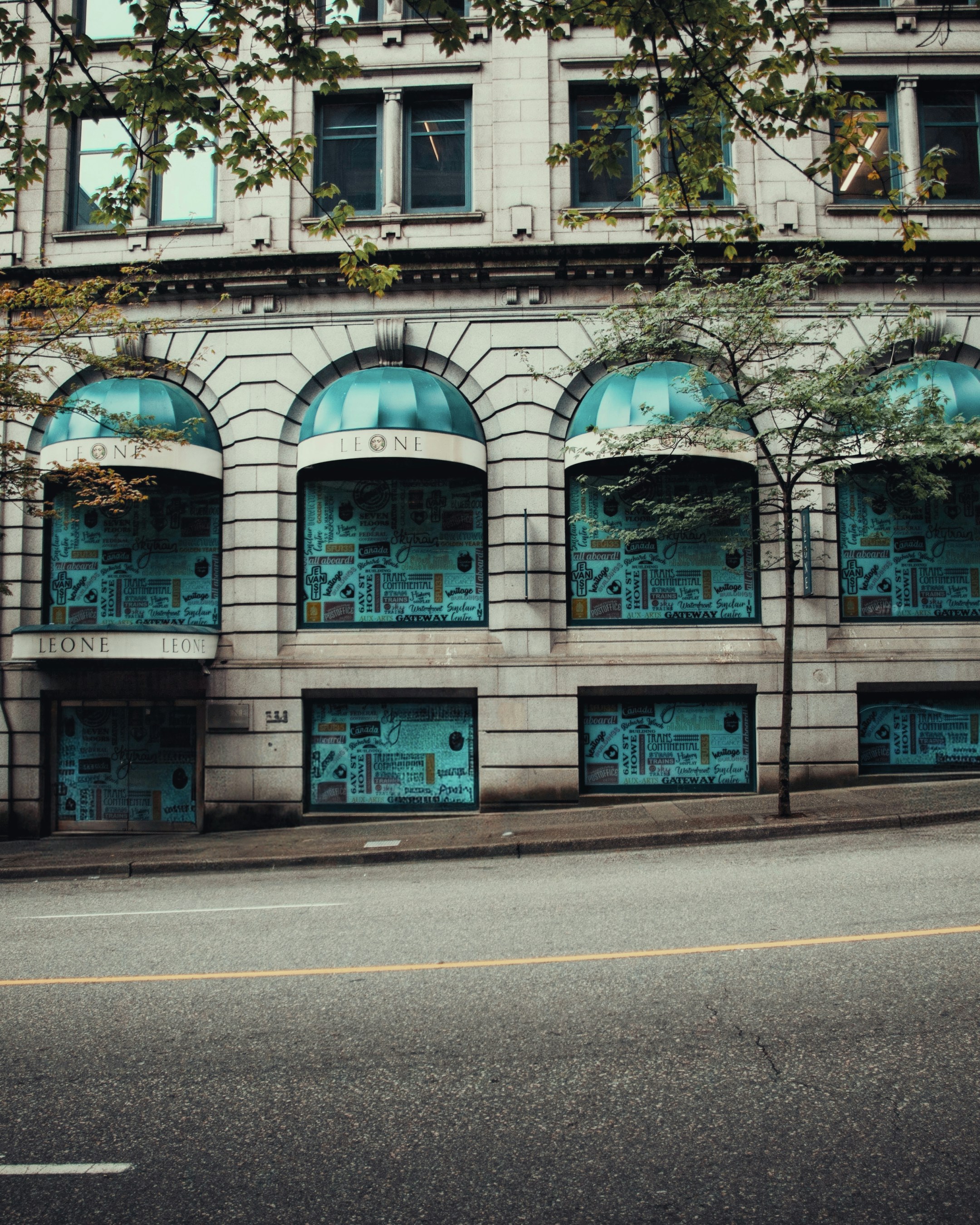 Un bâtiment en pierre avec des auvents turquoise et des fenêtres couvertes d’autocollants bleus graphiques