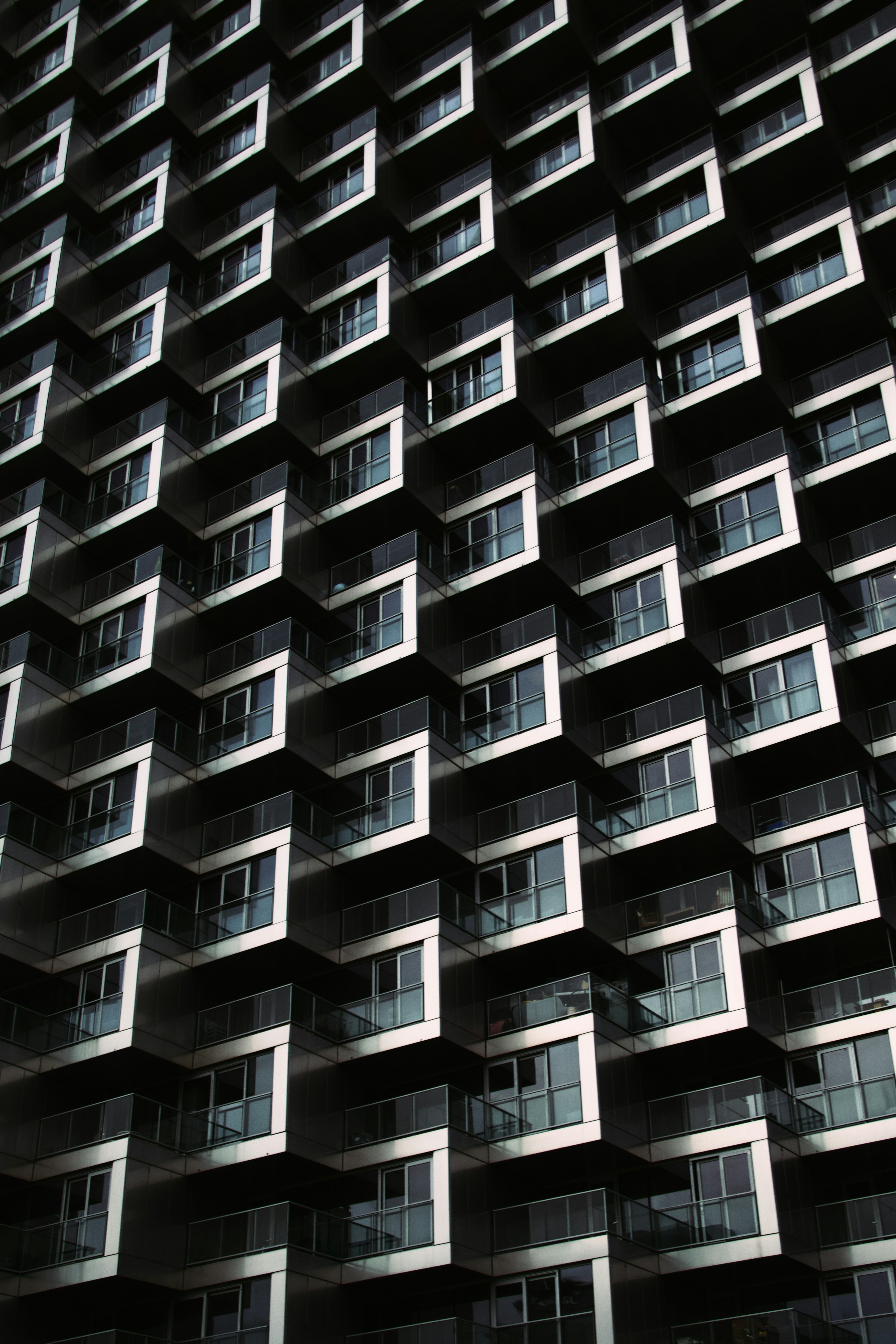 Une façade d’immeuble moderne avec balcons géométriques répétés et fenêtres vitrées