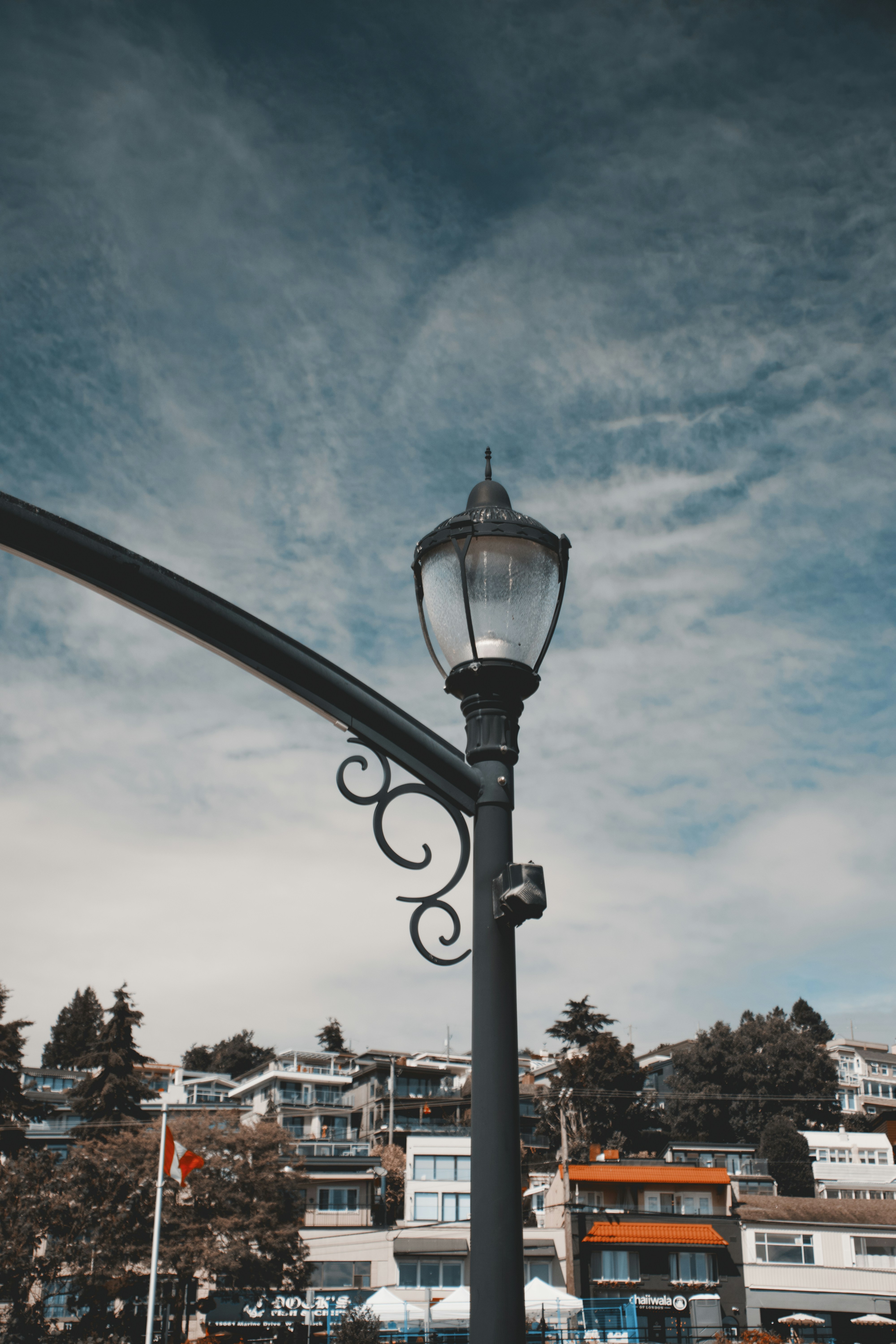 Un lampadaire en métal noir sur un ciel bleu avec des nuages épars