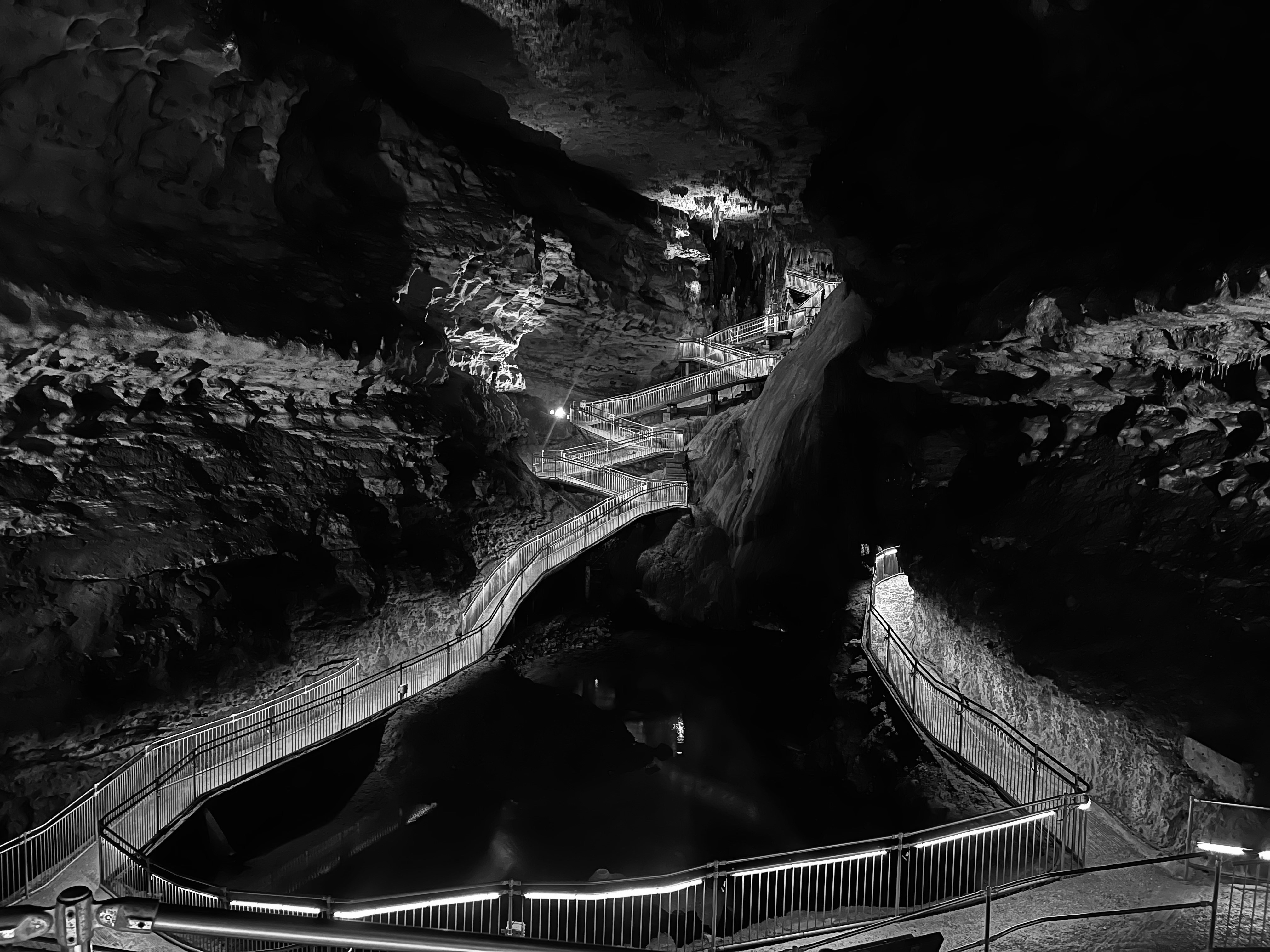 A winding metal walkway through a dark cavern with illuminated railings