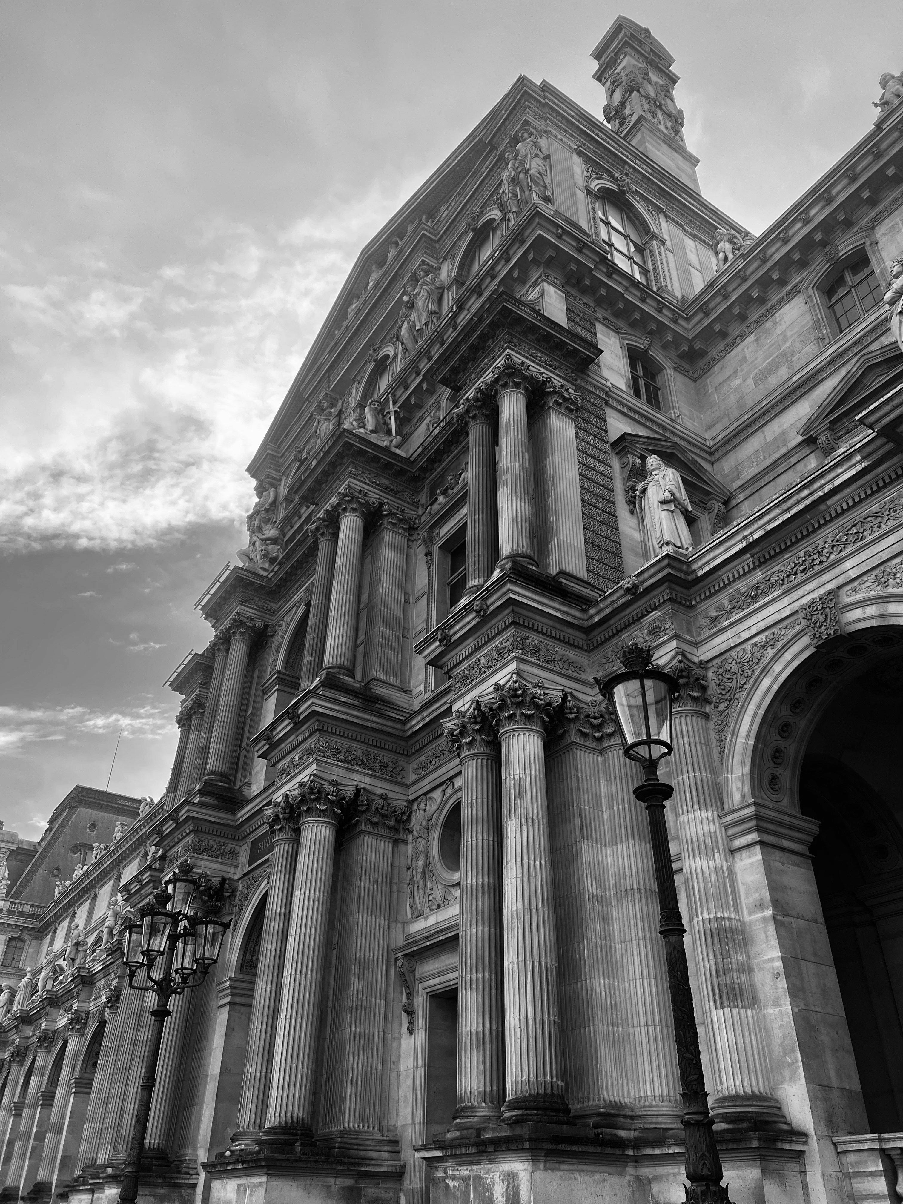 The ornate stone facade of the Louvre Museum in Paris with classical columns