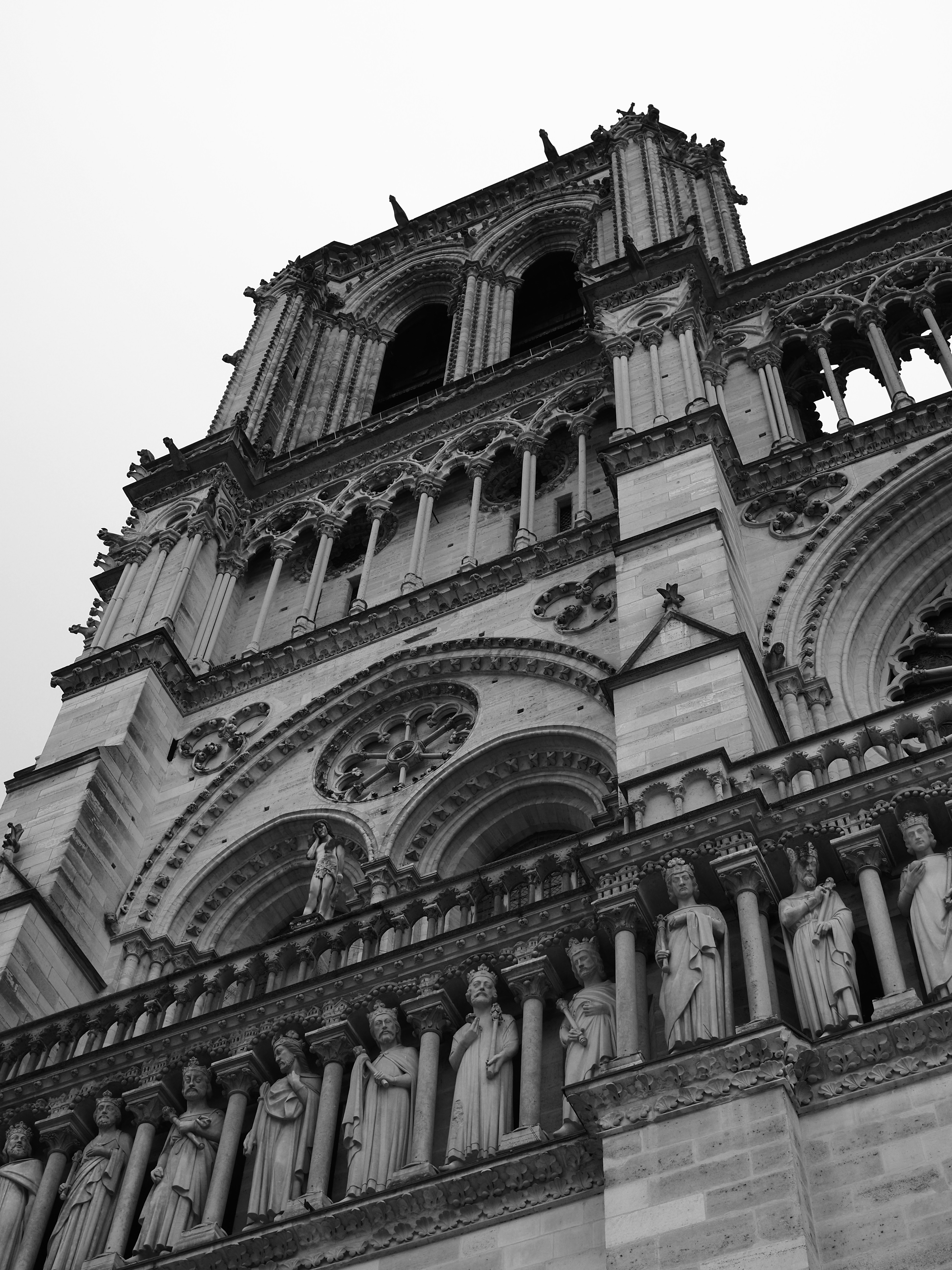 Low angle view of the stone facade and statues of Notre-Dame in Paris
