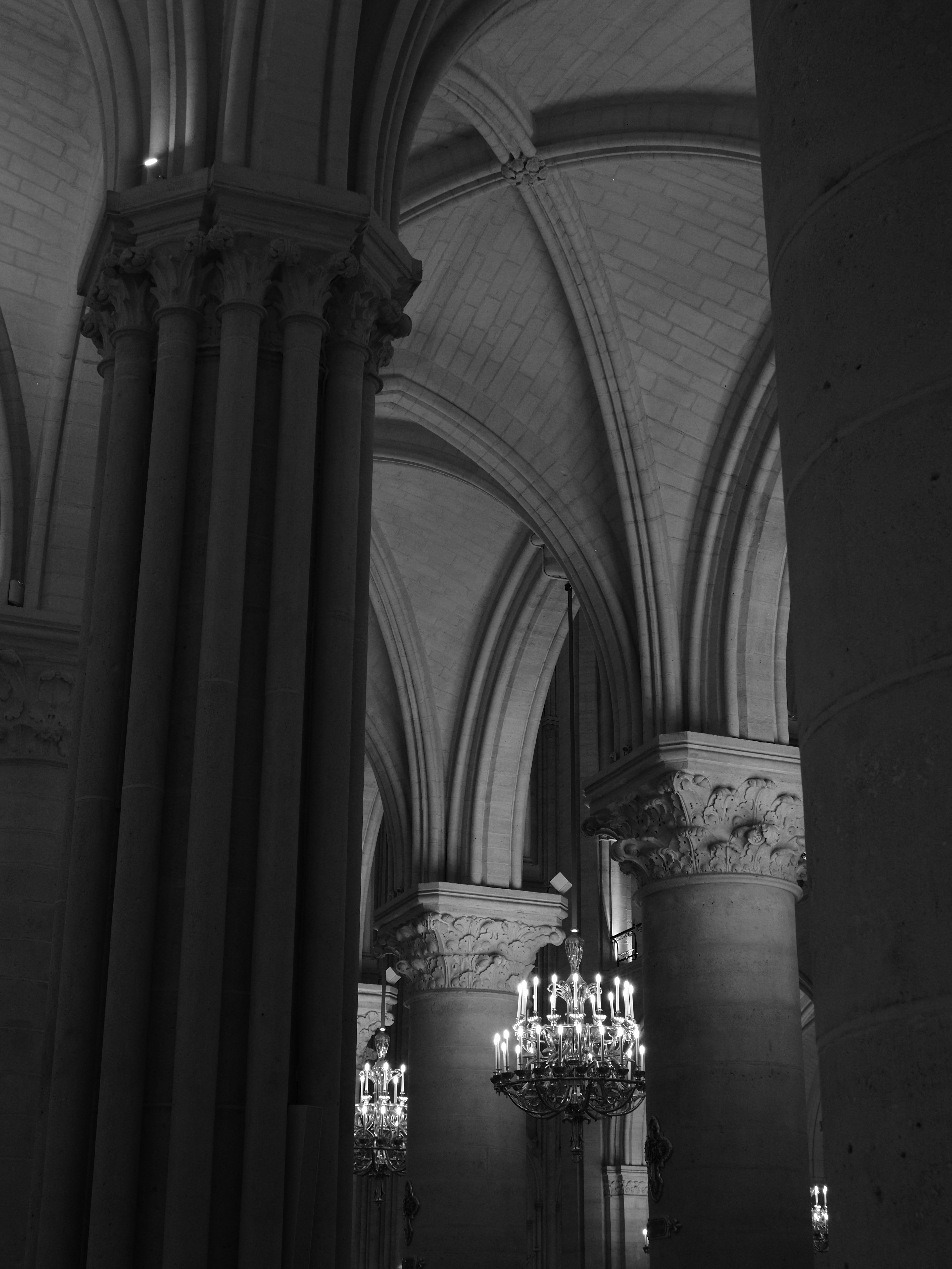 Gothic stone columns and vaulted ceilings with hanging chandeliers in a cathedral