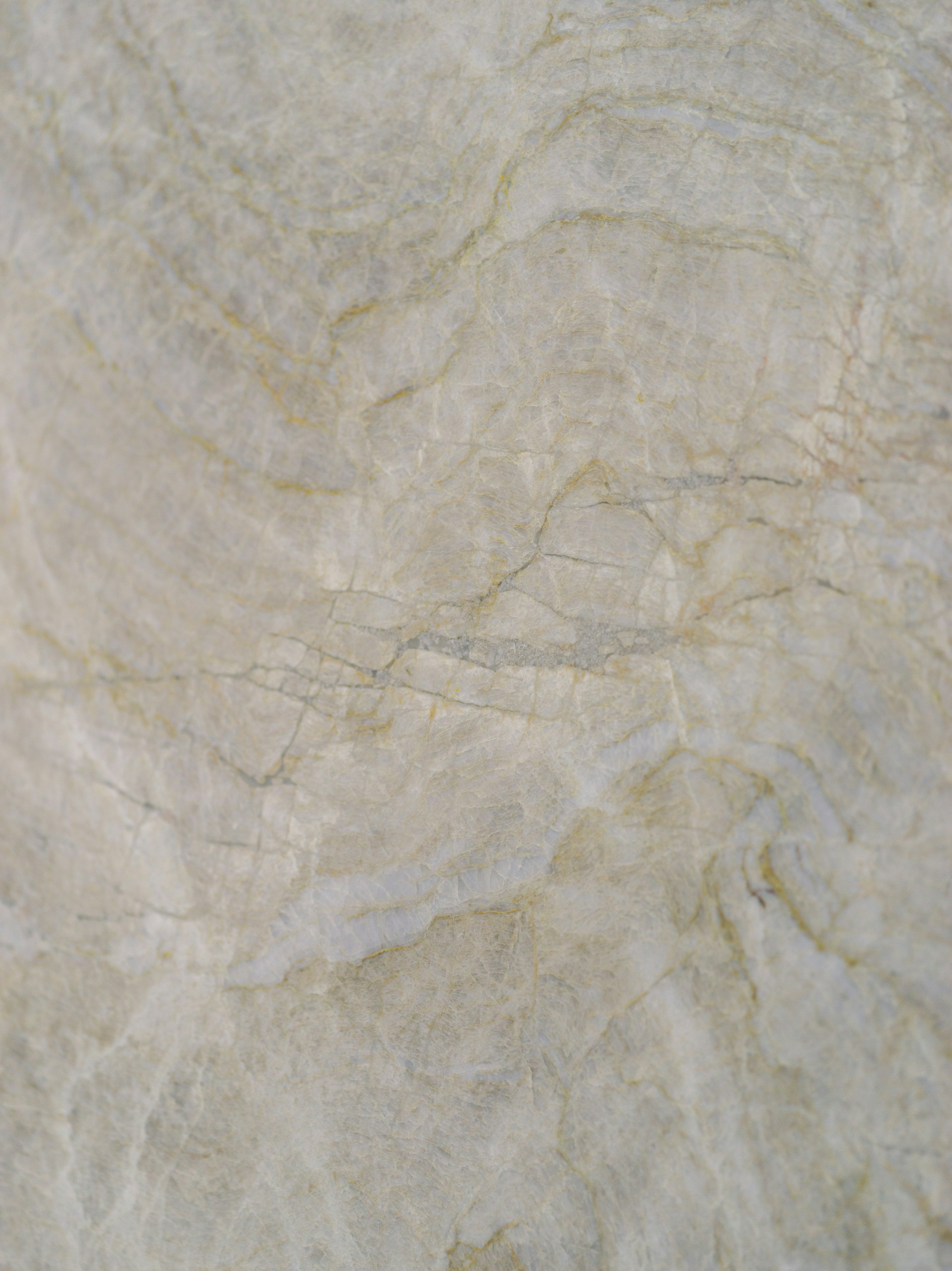 A polished stone slab with grey and gold veining throughout the surface