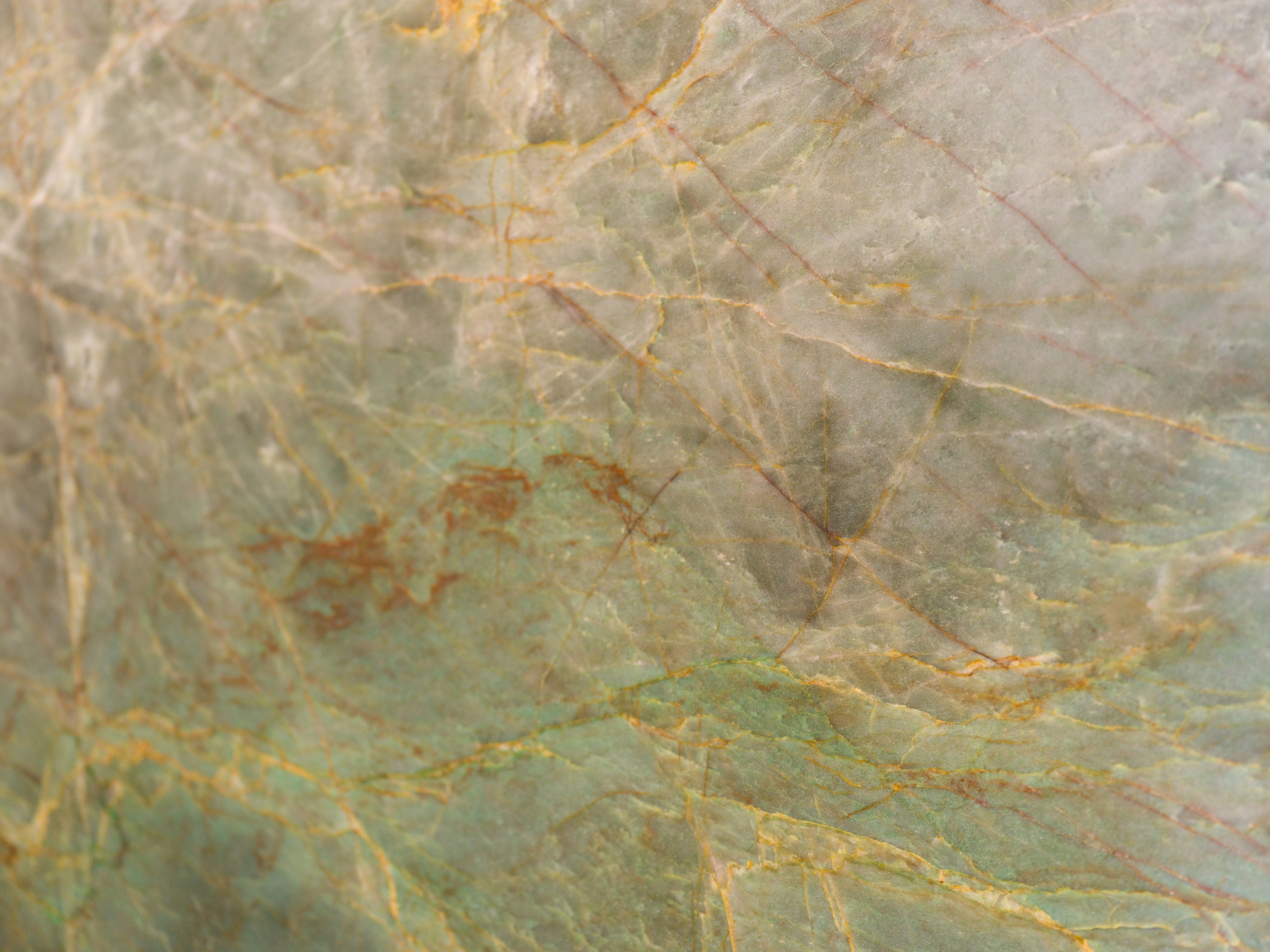 A polished green stone slab with intricate orange and white veining