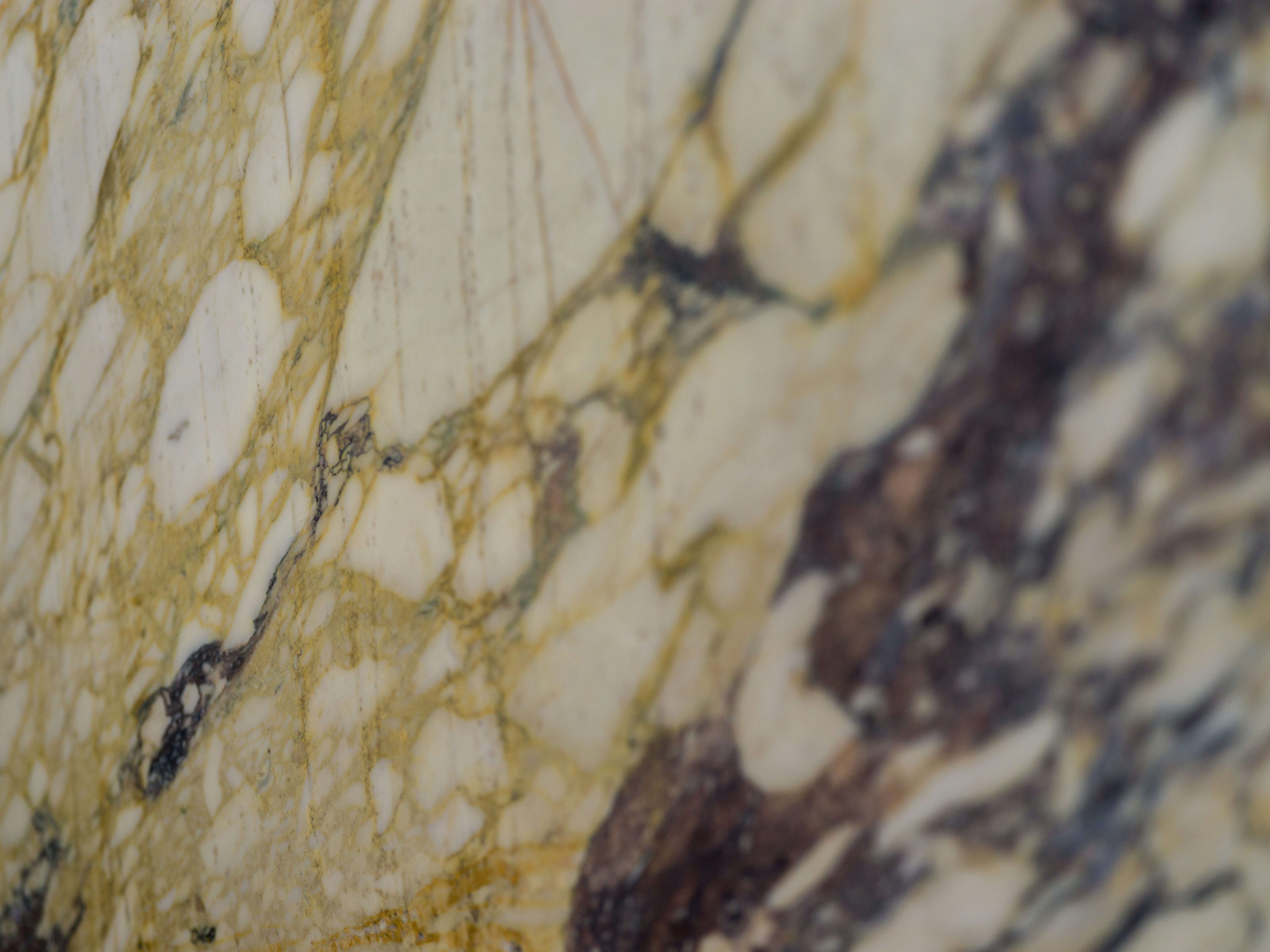 A close-up of polished marble with white, yellow, and dark brown veining
