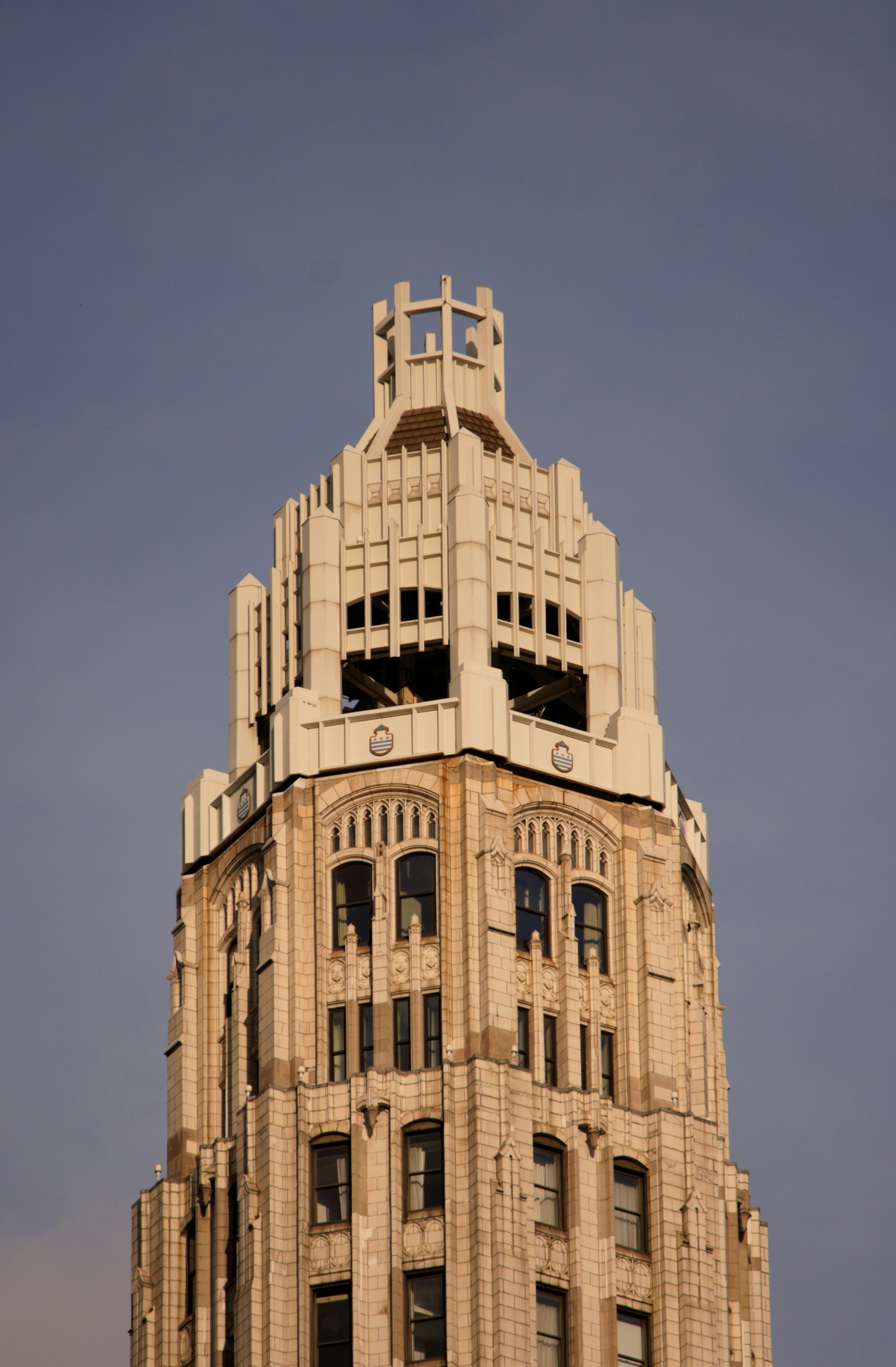 The ornate white stone tower of a skyscraper against a clear blue sky