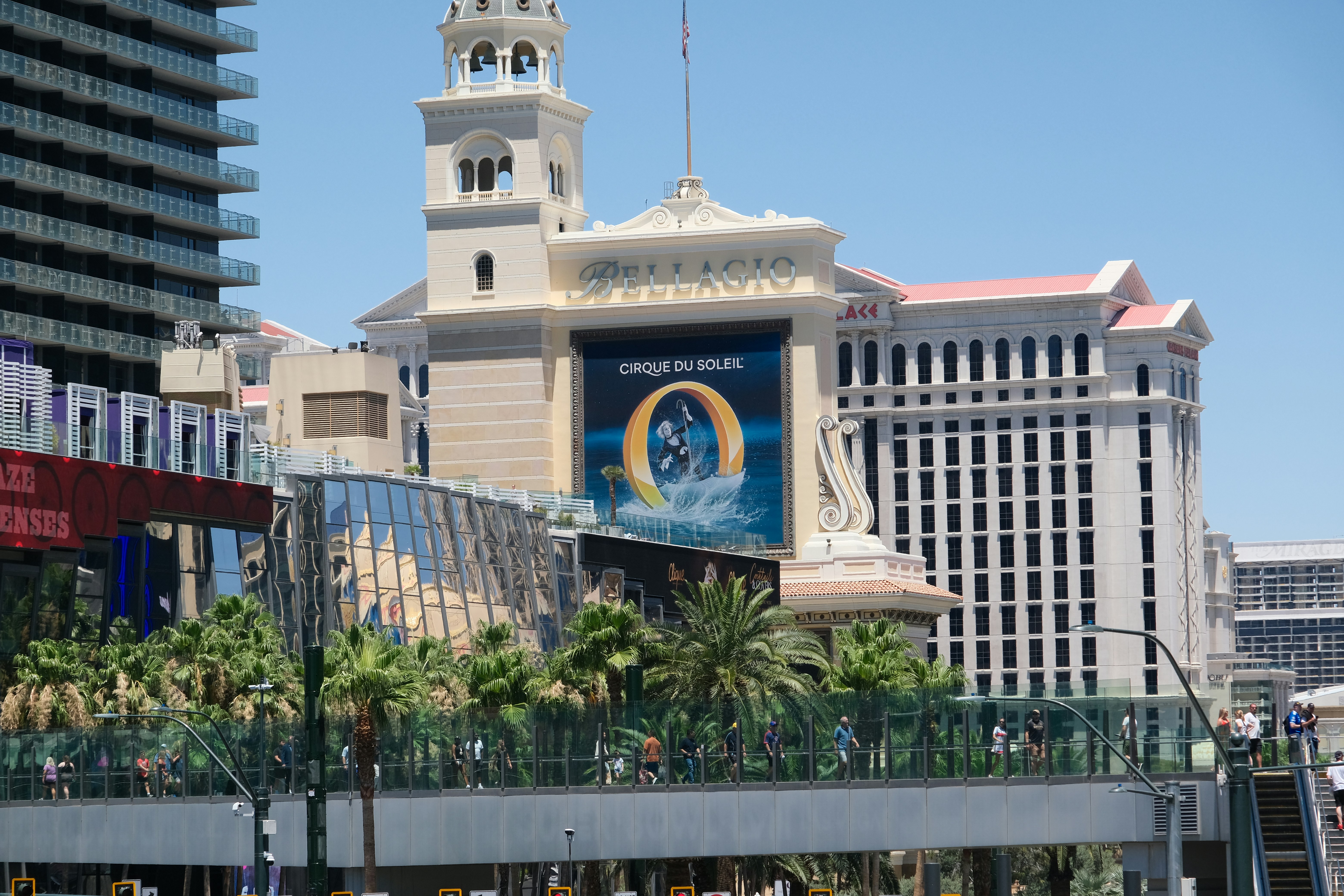 Pedestrians walking on a glass-walled bridge in front of the Bellagio hotel in Las Vegas