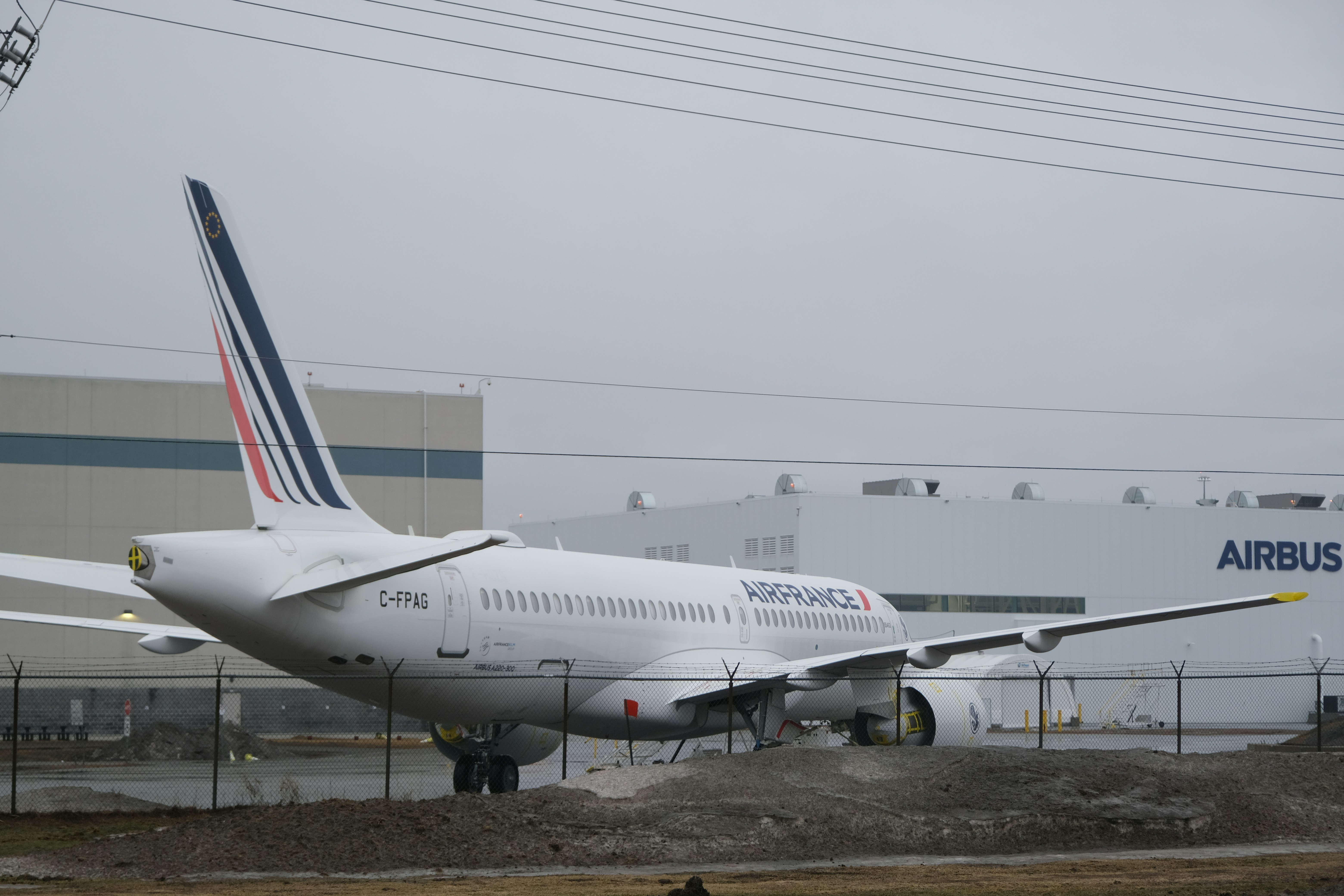 An Air France Airbus A220-300 parked on a tarmac near an Airbus facility