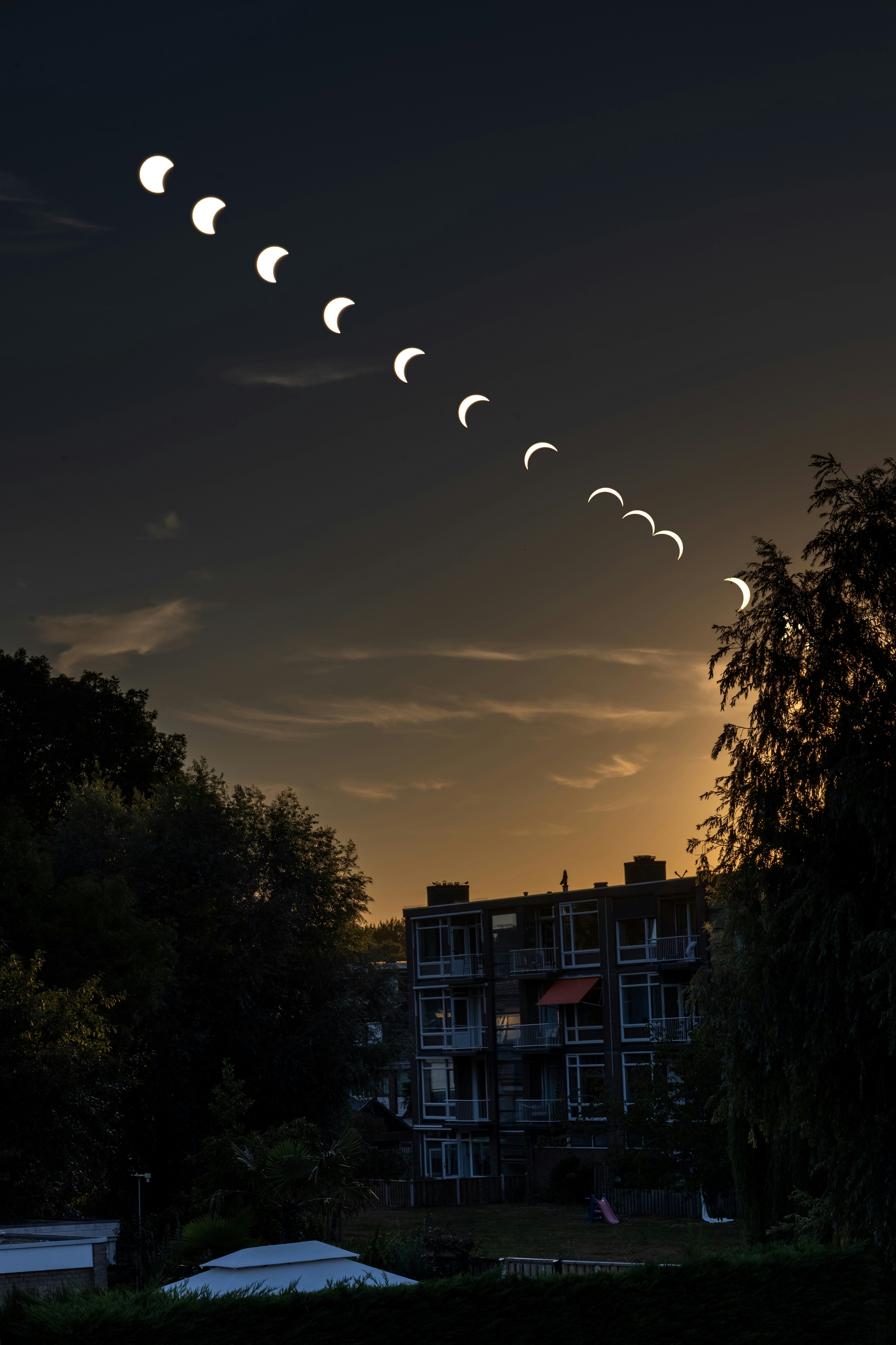 A composite image showing the phases of a solar eclipse above an apartment building