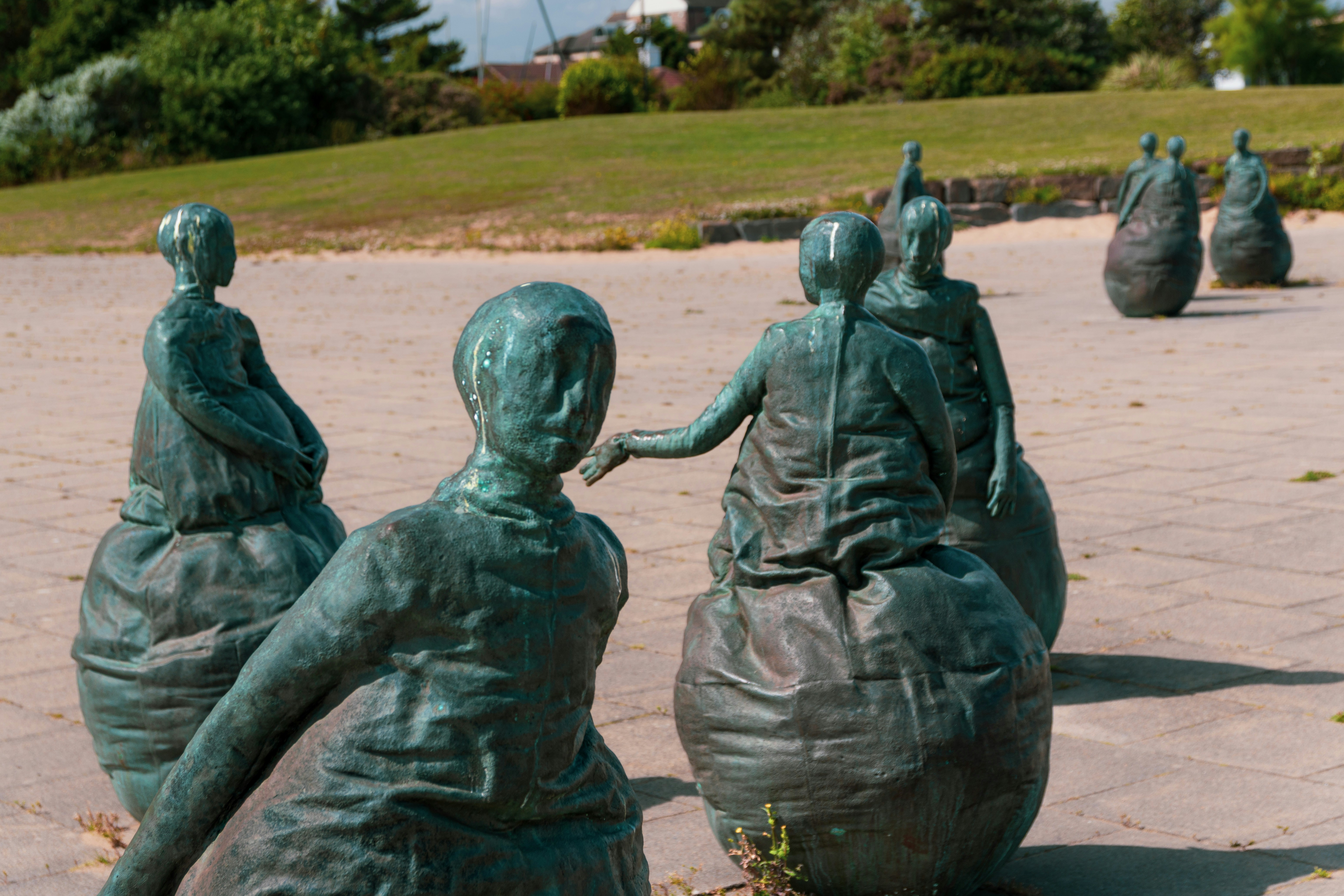 A group of bronze sculptures of people on spherical bases in a park