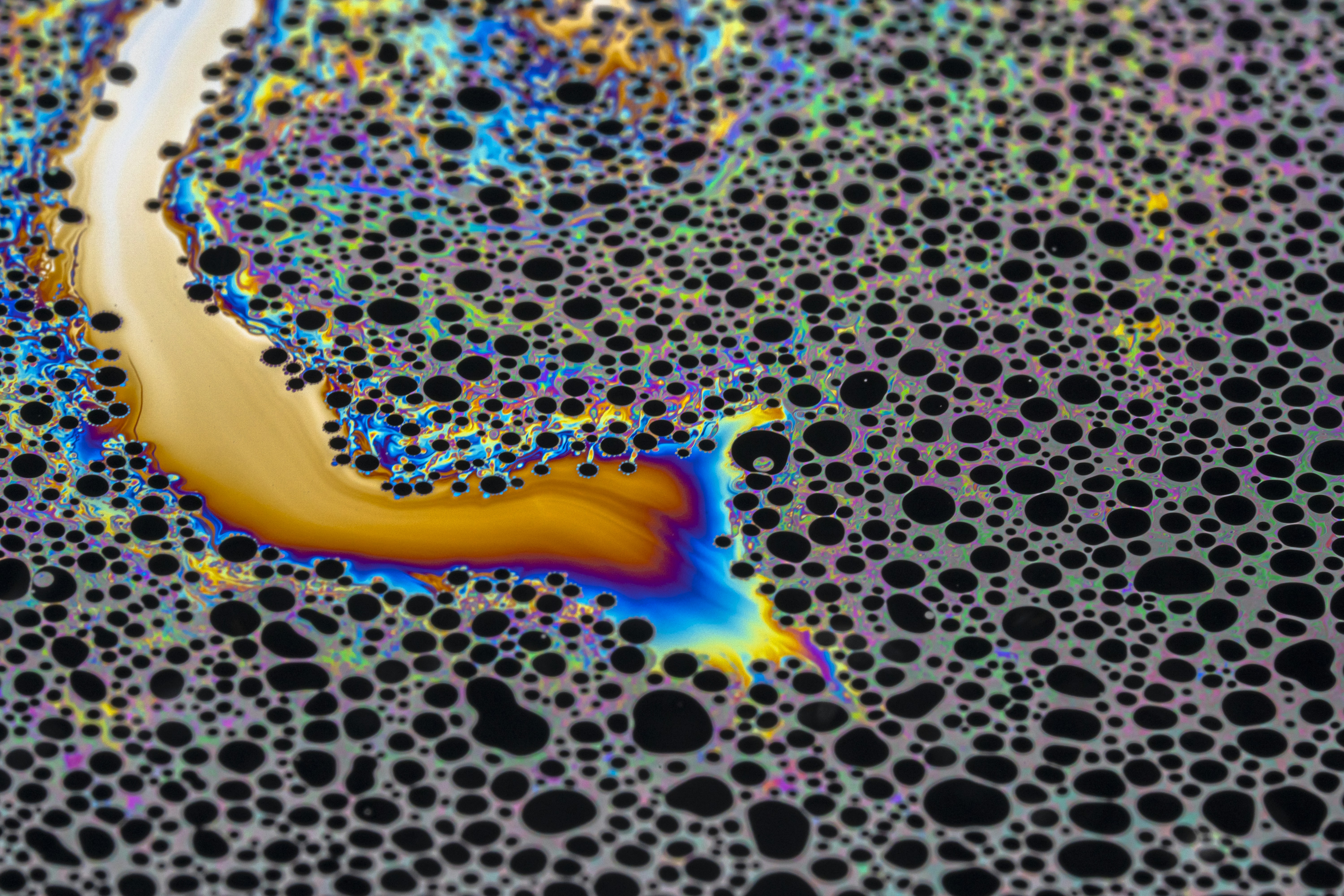 Iridescent soap bubbles with black circular patterns and vibrant rainbow colors
