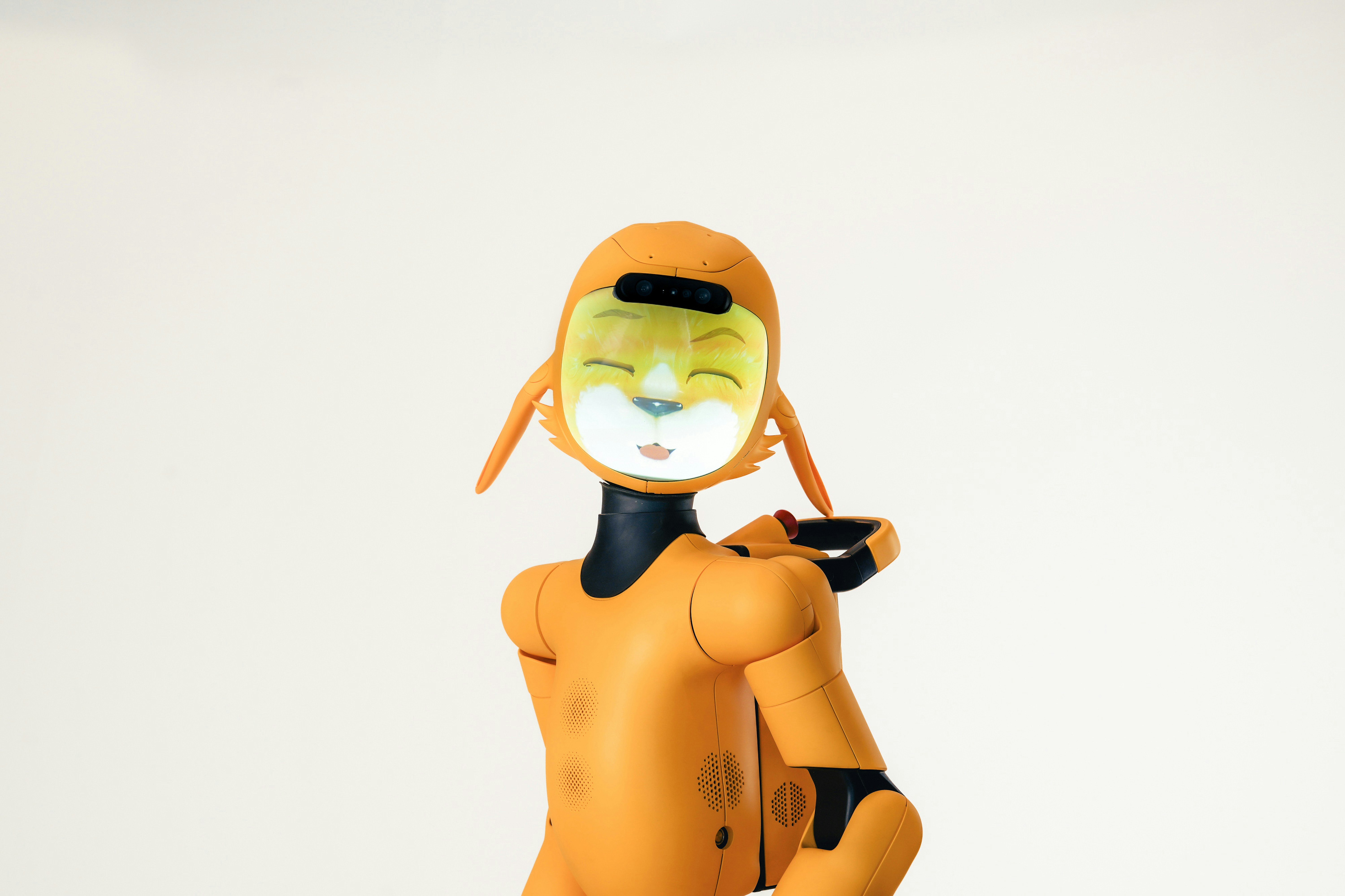 An orange humanoid robot with a digital screen face displaying a cat avatar