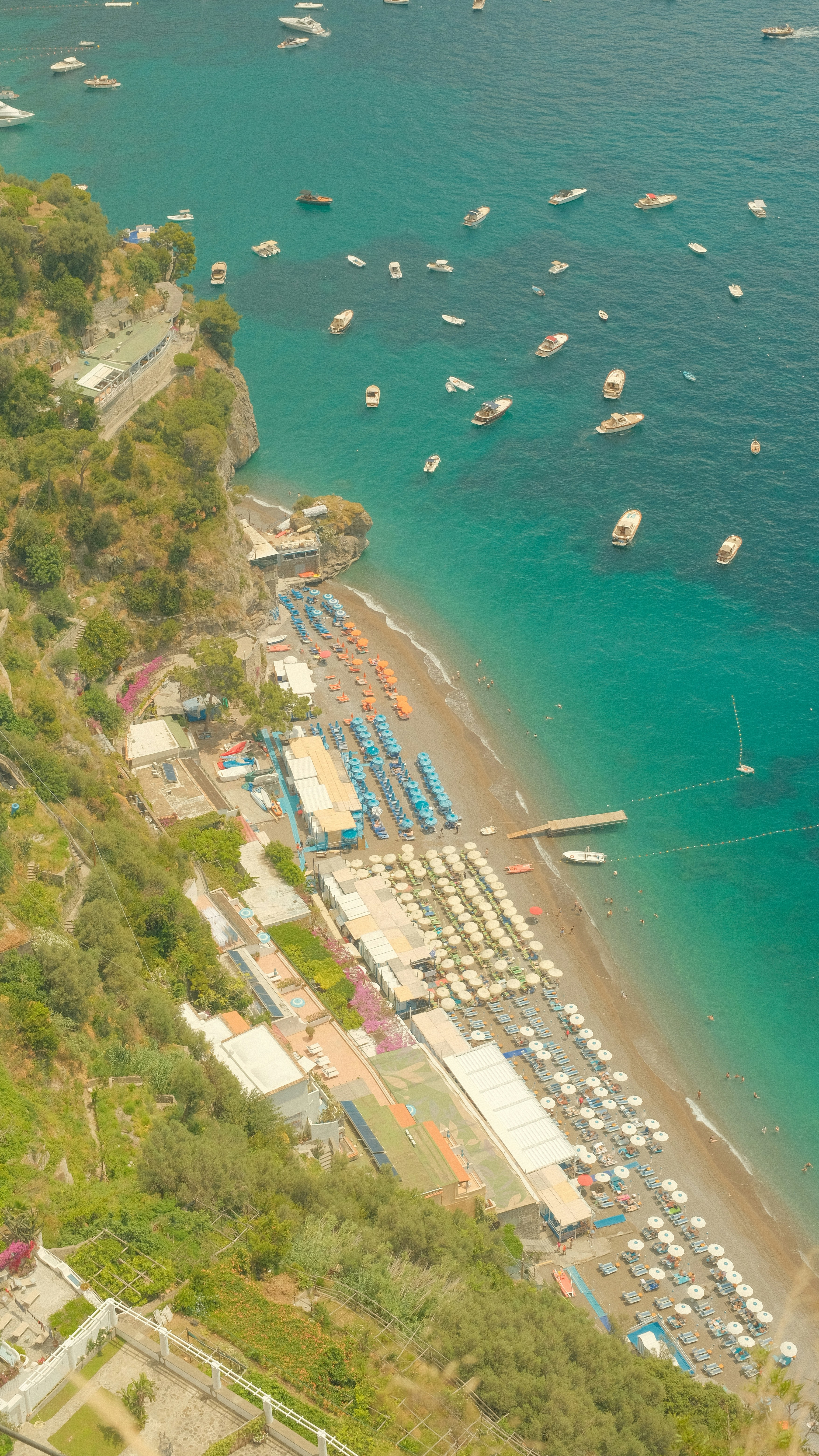 Aerial view of a beach with rows of umbrellas and boats in Positano