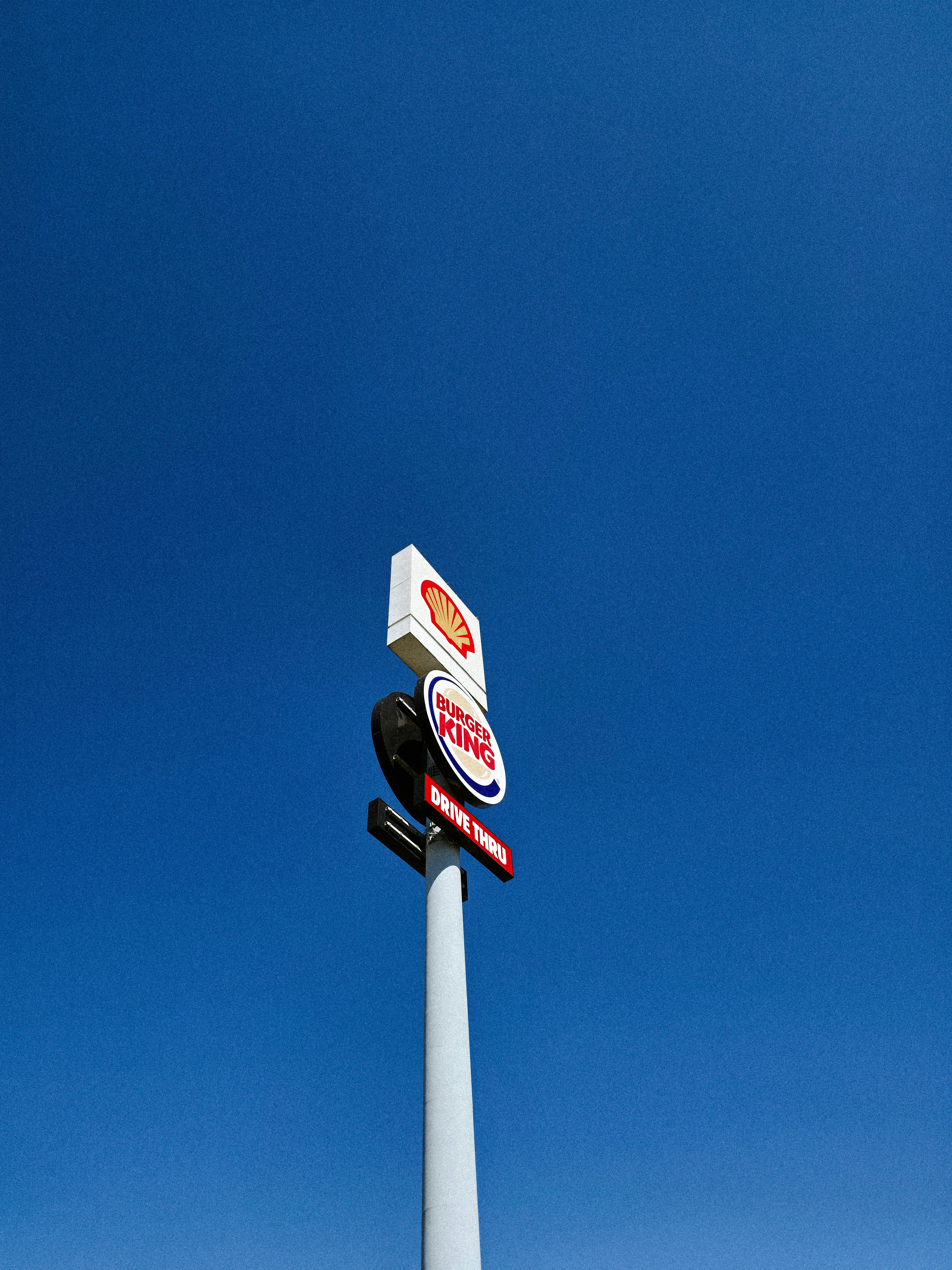 A tall sign with Shell and Burger King logos against a clear blue sky