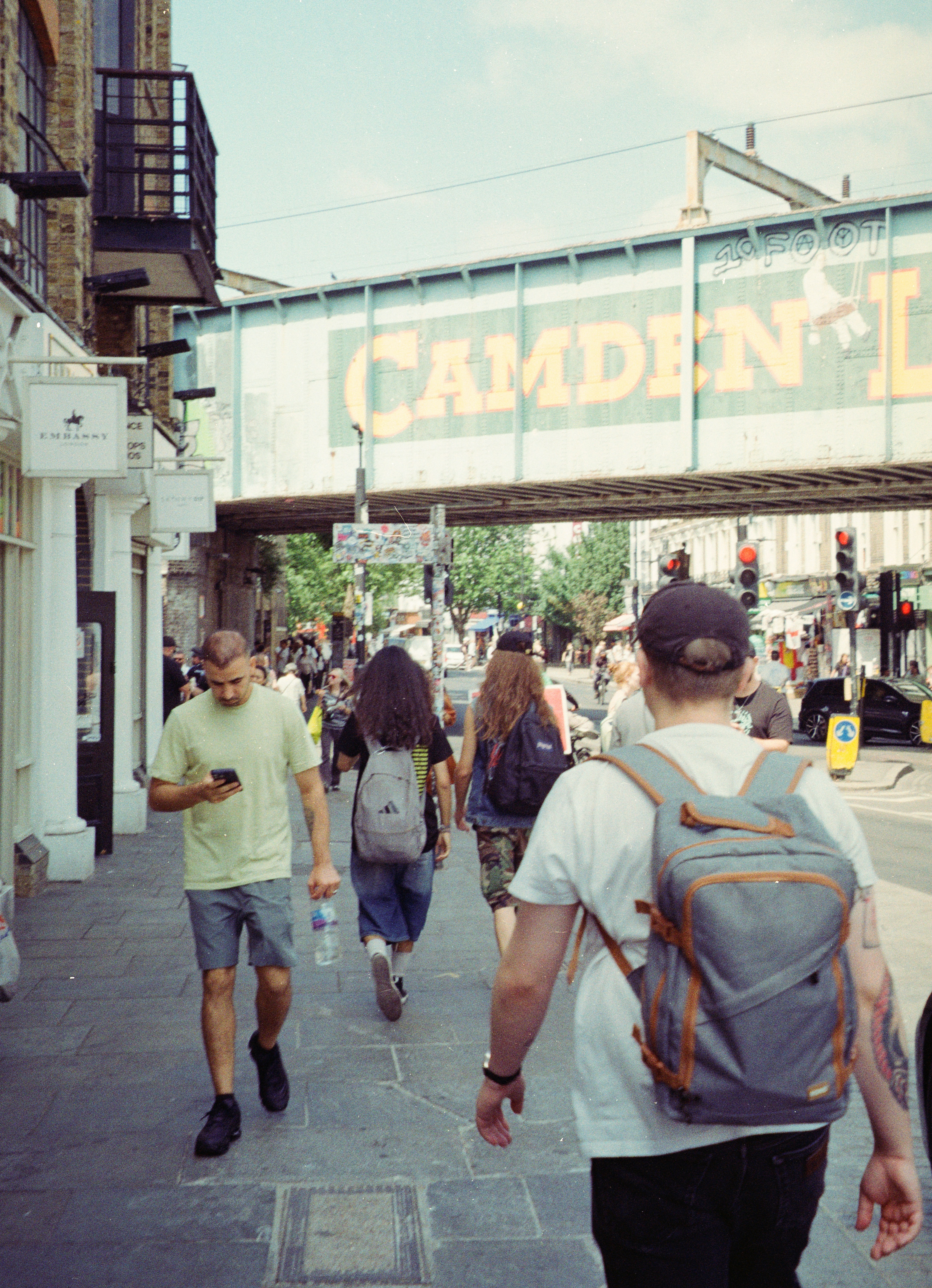 Des gens marchant sur un trottoir sous un pont ferroviaire à Camden, Londres