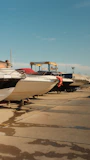 Motorboats on trailers in a paved boatyard under a clear blue sky