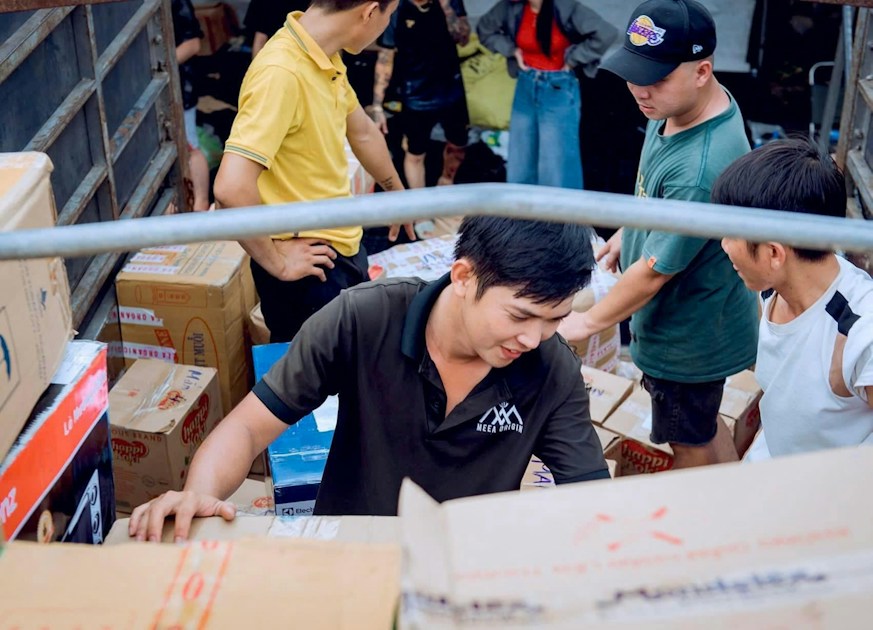 A group of people loading cardboard boxes into the back of a truck